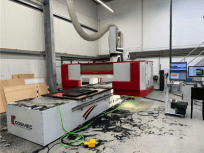 Máquina CNC Cosmec 515 em oficina com um terminal de computador, mostrando uma vista frontal e poeira espalhada na superfície.