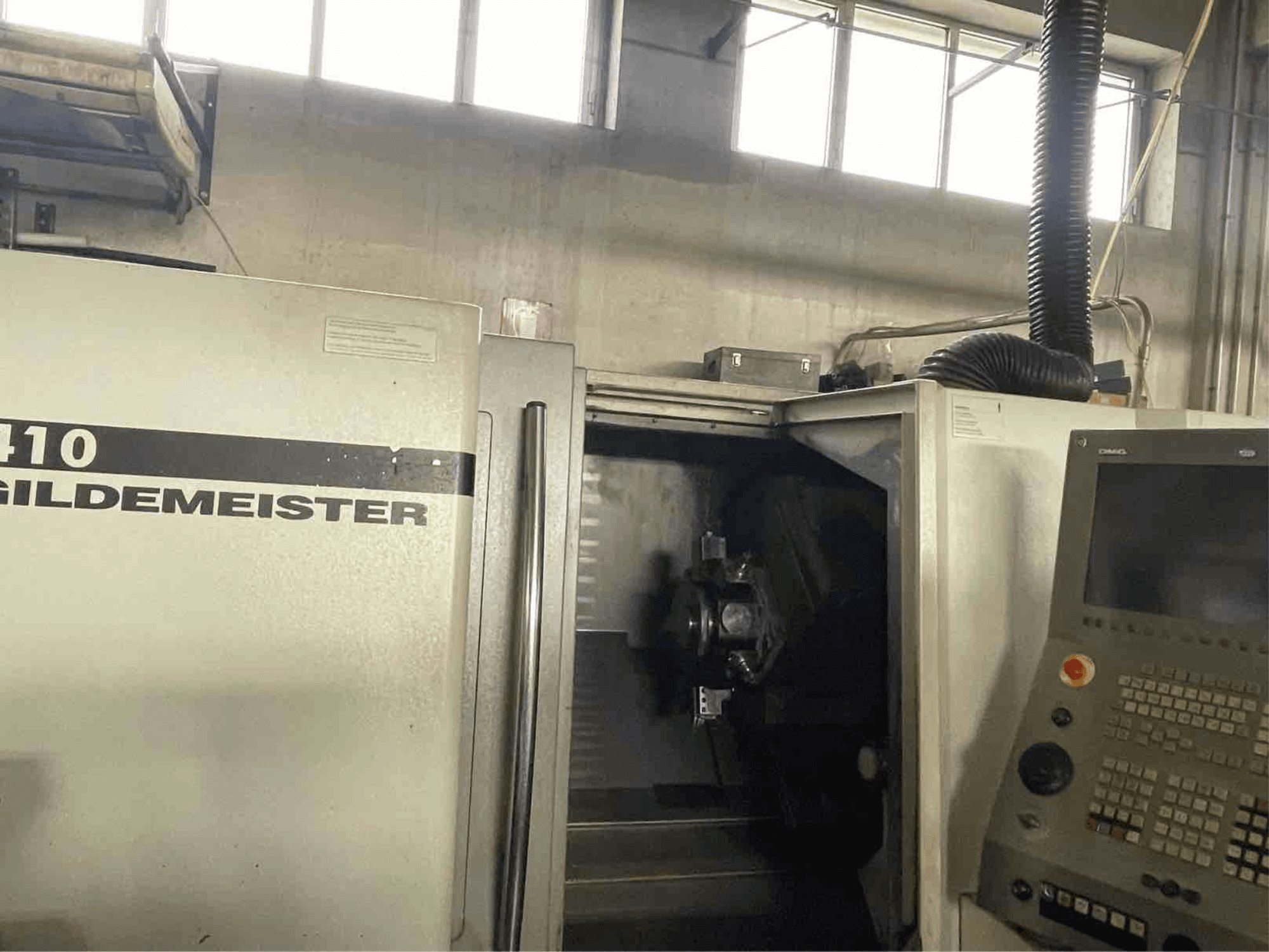 Torneiro horizontal DMG CTX410, vista frontal, mostrando o painel de controlo e os componentes de maquinação visíveis no interior.