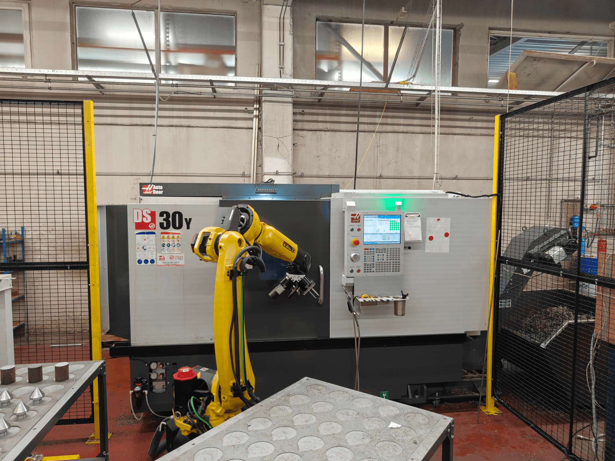 Torno horizontal HAAS DS30Y com braço robótico, vista frontal, mostrando o painel de controlo e a área de trabalho.
