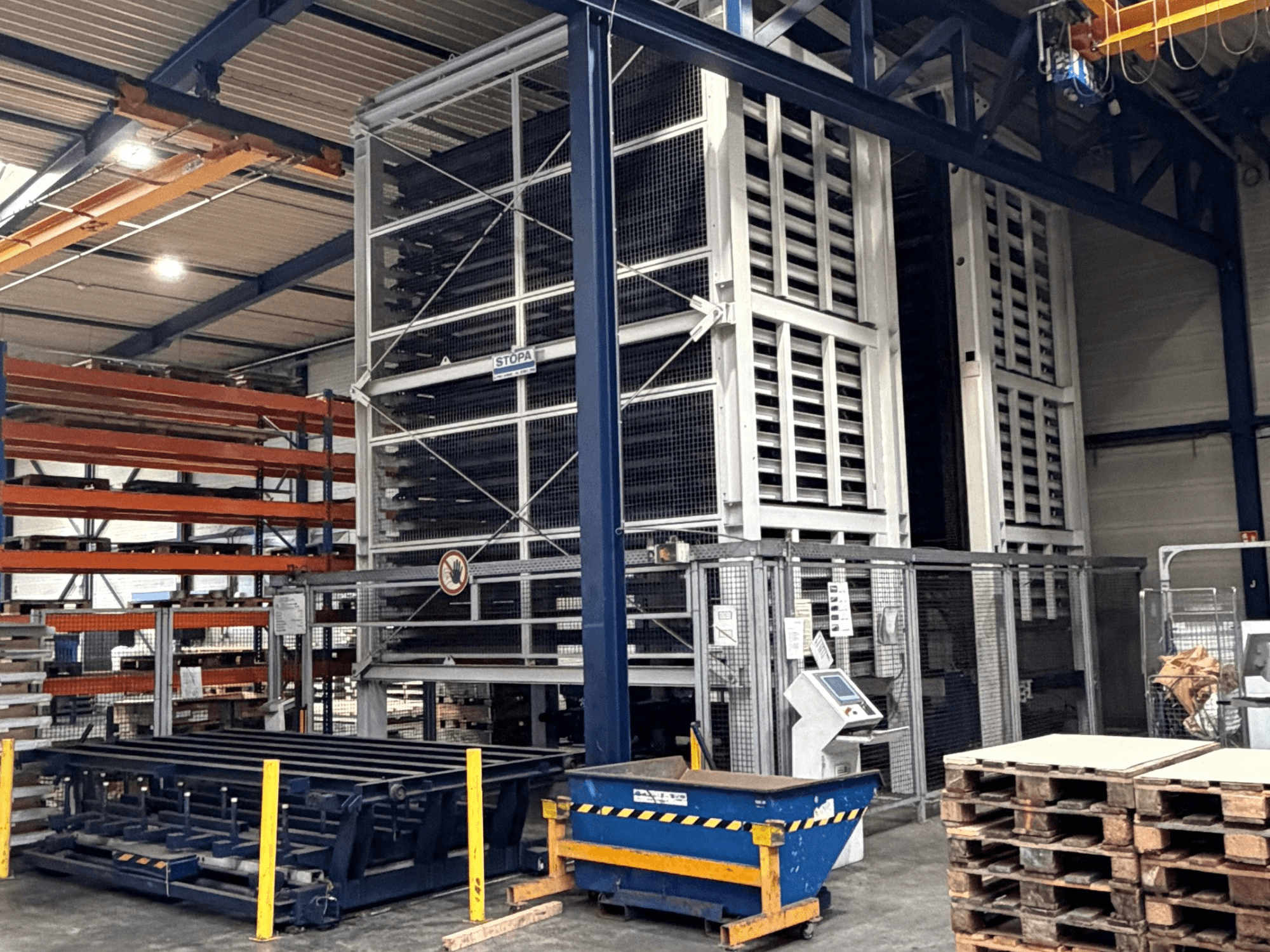 Sistema de automação TRUMPF STOPA 4000x2000 num armazém, vista lateral mostrando as estantes e o painel de controlo na área de armazenamento.