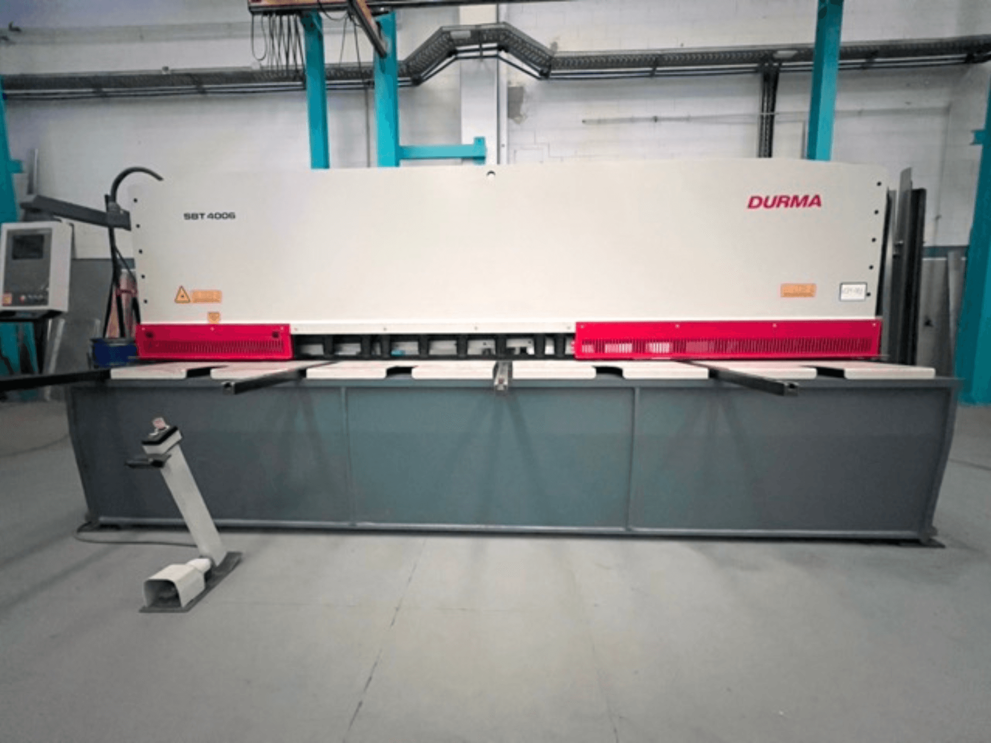 Máquina de corte CNC Durma SBT 4006 em vista frontal, com uma base cinzenta e detalhes em vermelho, pronta a funcionar numa fábrica.