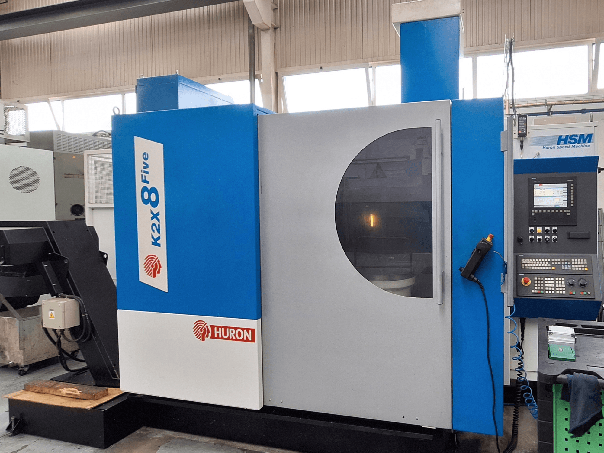Fresadora de pórtico Huron K2X 8 Five, vista frontal que mostra o painel de controlo e a grande janela de visualização.