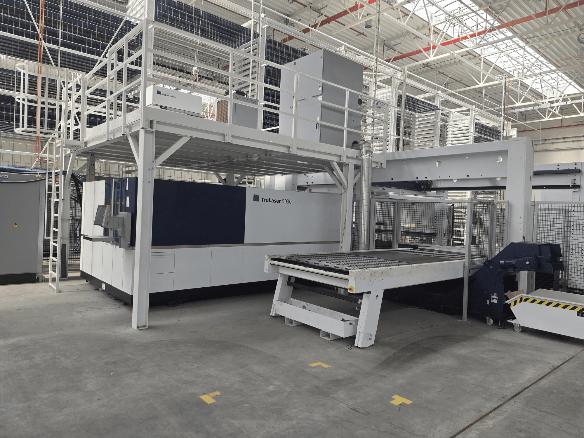 Máquina TRUMPF TruLaser 5030 fiber L76 FMC numa oficina, vista frontal que mostra a área de corte e o mecanismo de carga e descarga.