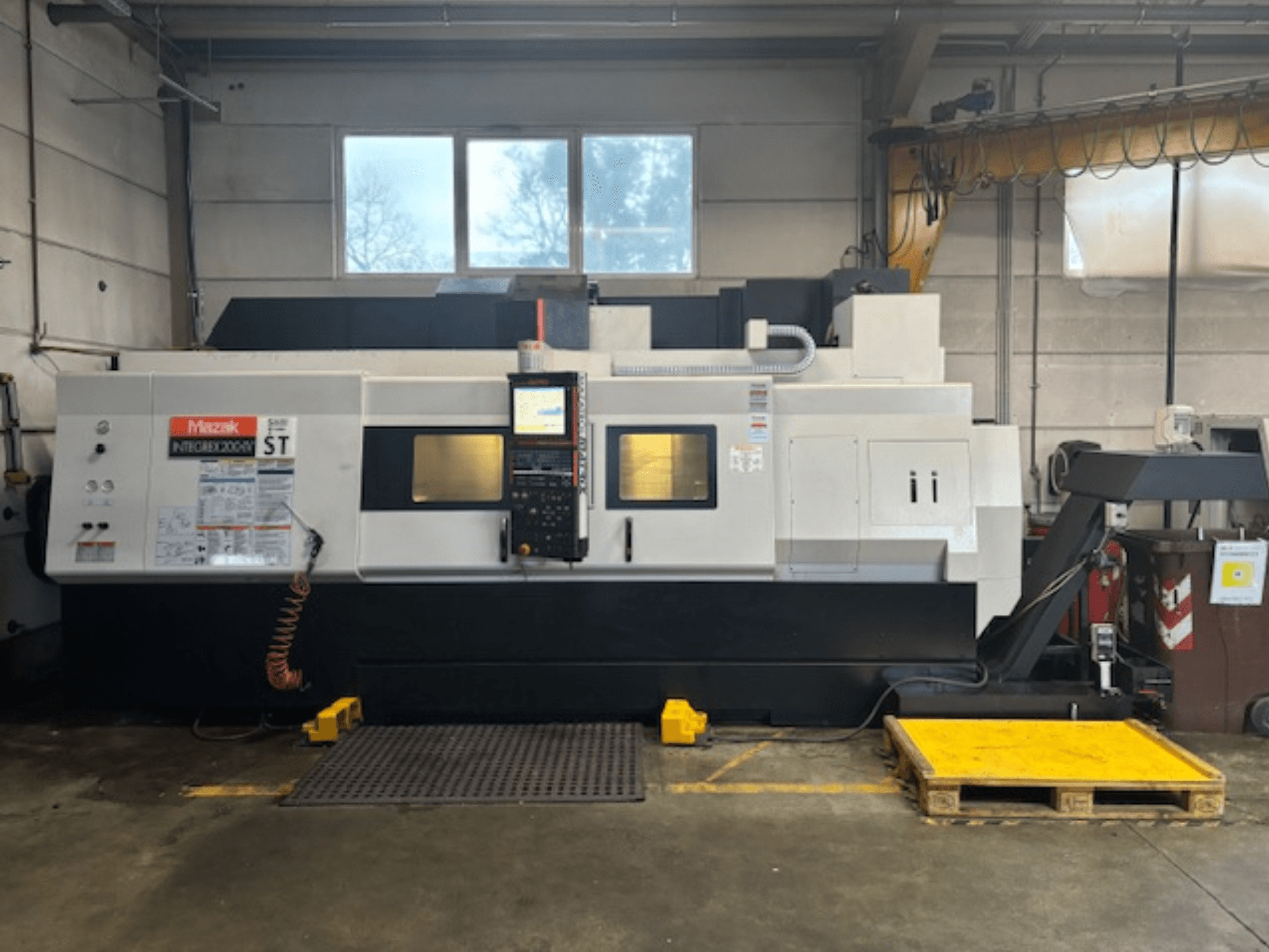 Mazak Integrex 200 SY ST, vista lateral, mostrando o painel de controlo, os visores de operação e as linhas de refrigeração numa oficina.