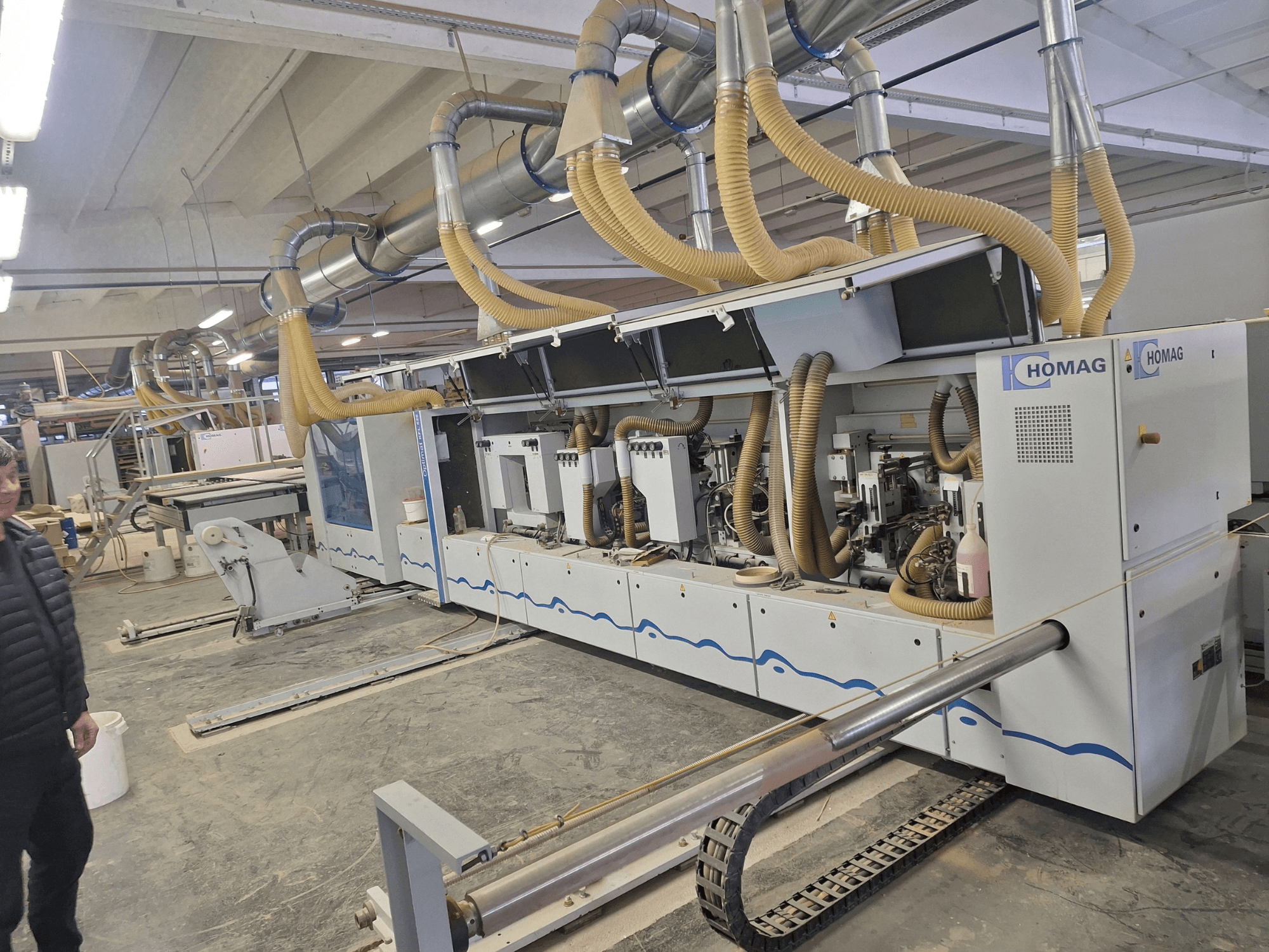 Máquina para trabalhar madeira da HOMAG numa fábrica, vista frontal com vários fusos e sistema de extração de poeiras.