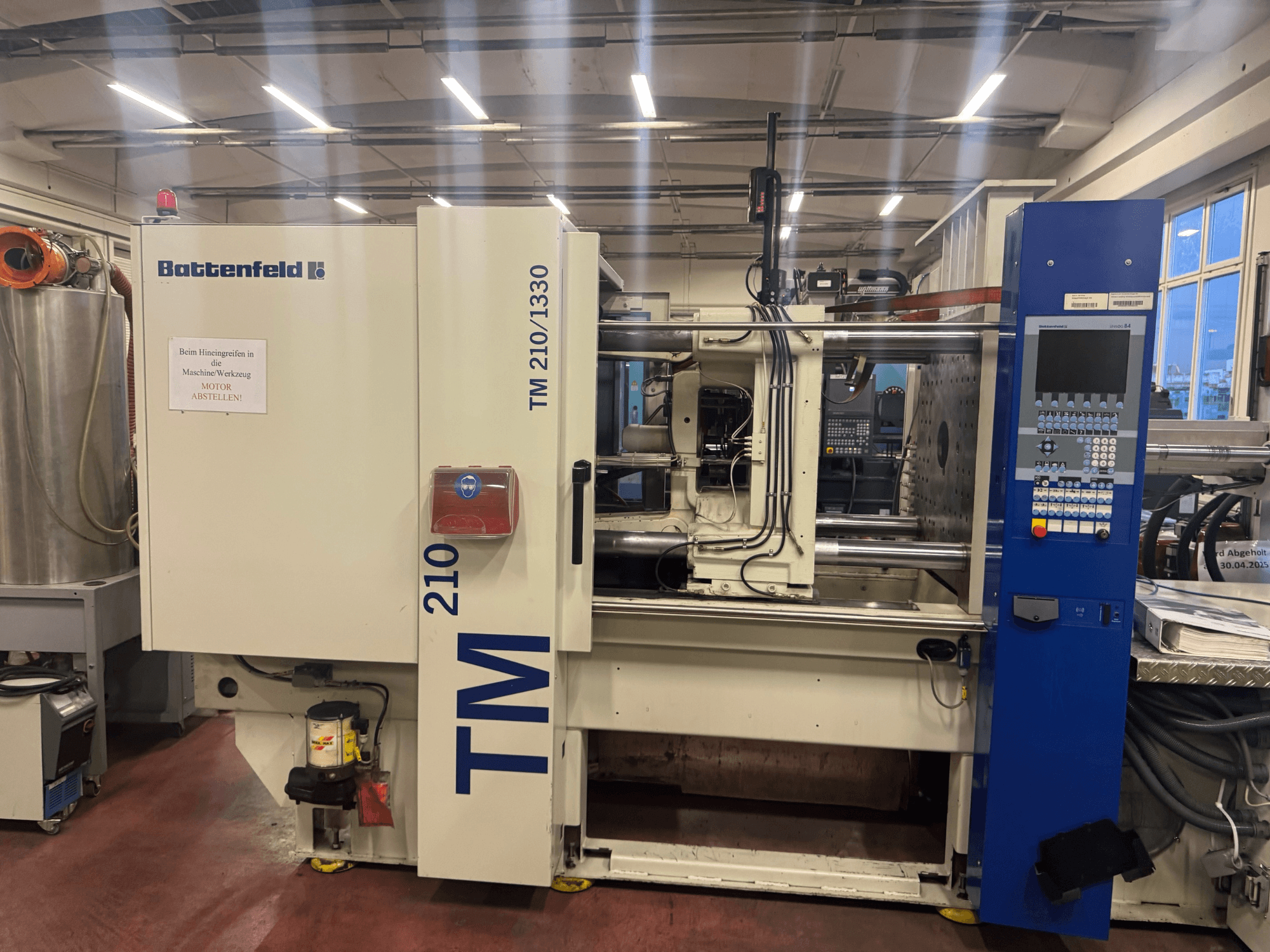 Máquina de moldagem por injeção hidráulica Battenfeld TM 210/1330, vista frontal, mostrando o painel de controlo e os componentes da máquina.