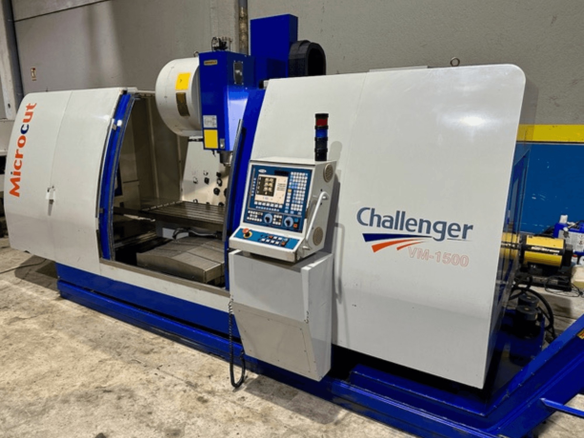 Máquina CNC Microcut Challenger VM-1500, vista frontal, com painel de controlo, espaço de trabalho e uma base azul.