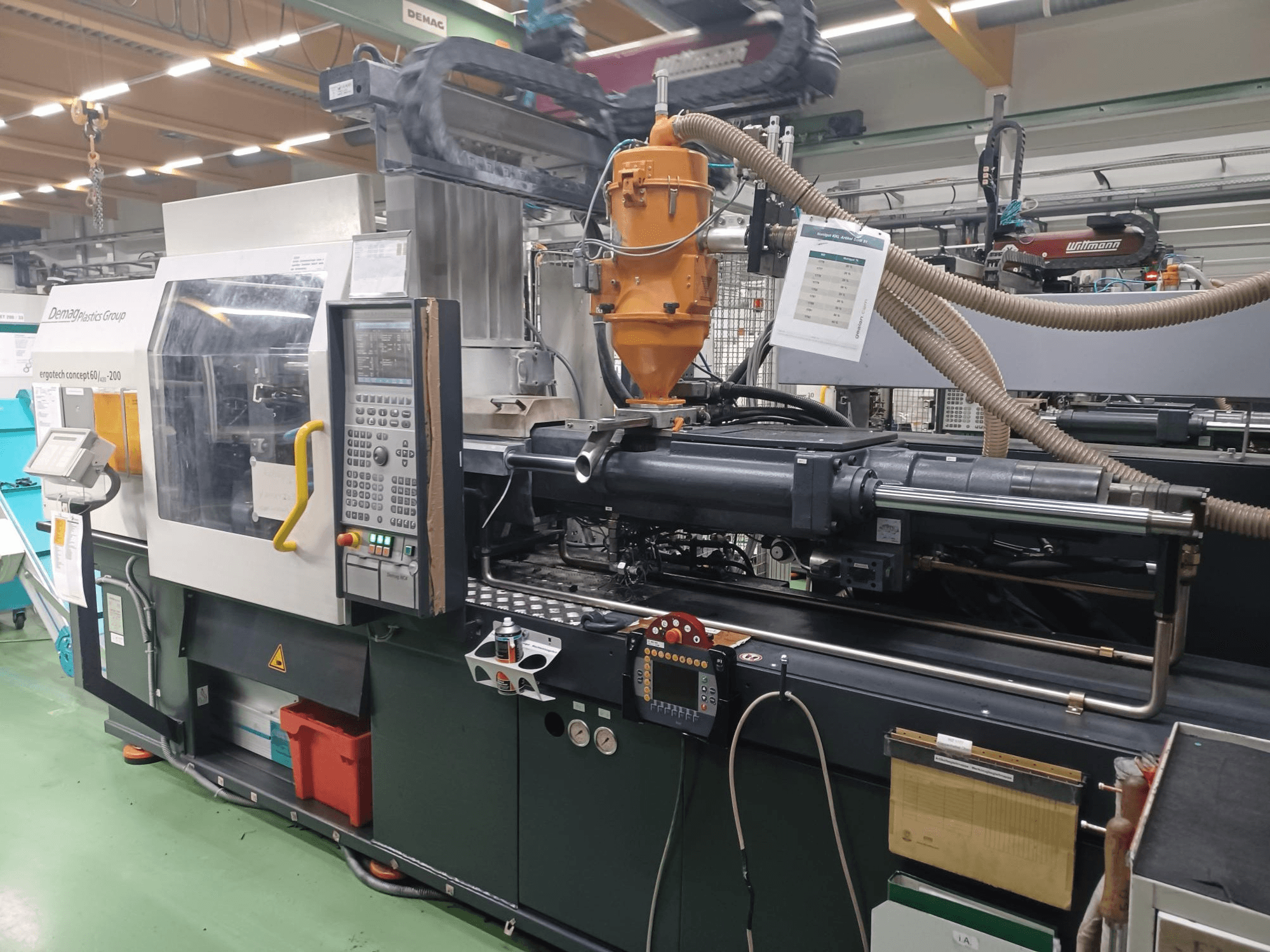 Máquina de moldagem por injeção Demag Ergotech 200, vista frontal, com painel de controlo, bocal e componentes operacionais visíveis.