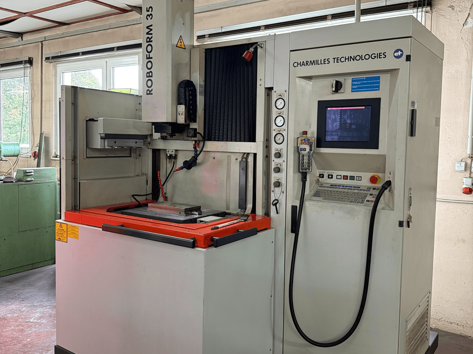 Máquina Roboforn 35 da Charmilles Technologies, vista frontal, mostrando o painel de controlo, ferramentas montadas e etiquetas de segurança.