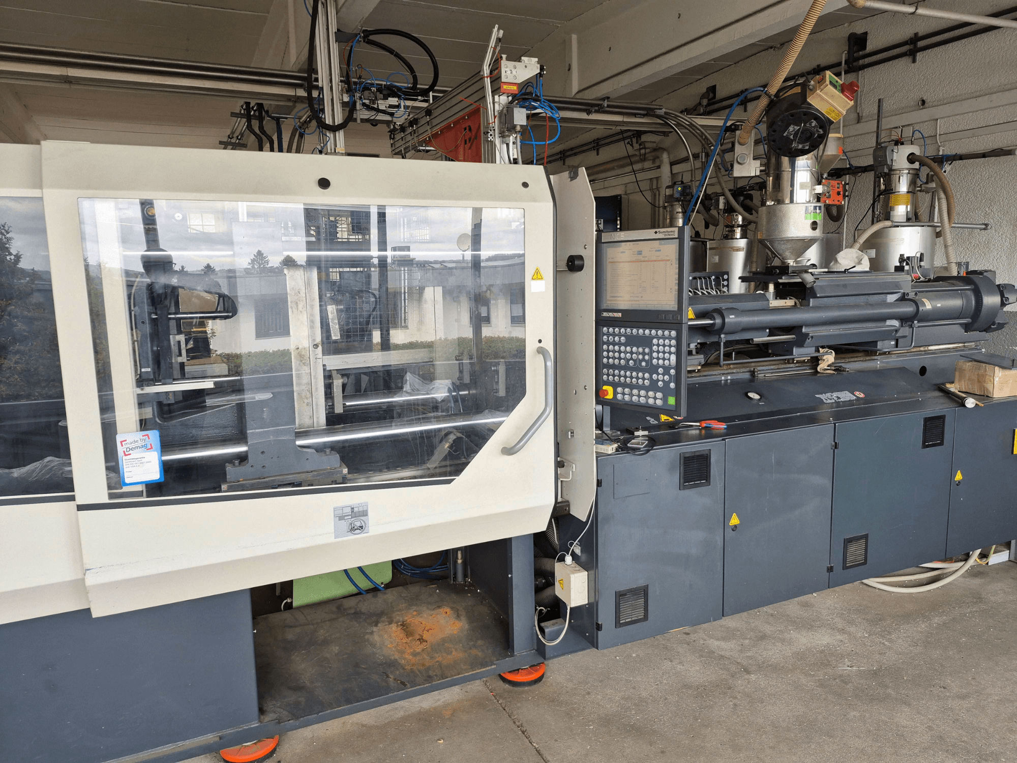 Máquina de moldagem por injeção hidráulica, SUMITOMO SHI DEMAG Systec 210/580-1450, vista frontal com painel de controlo e componentes visíveis.