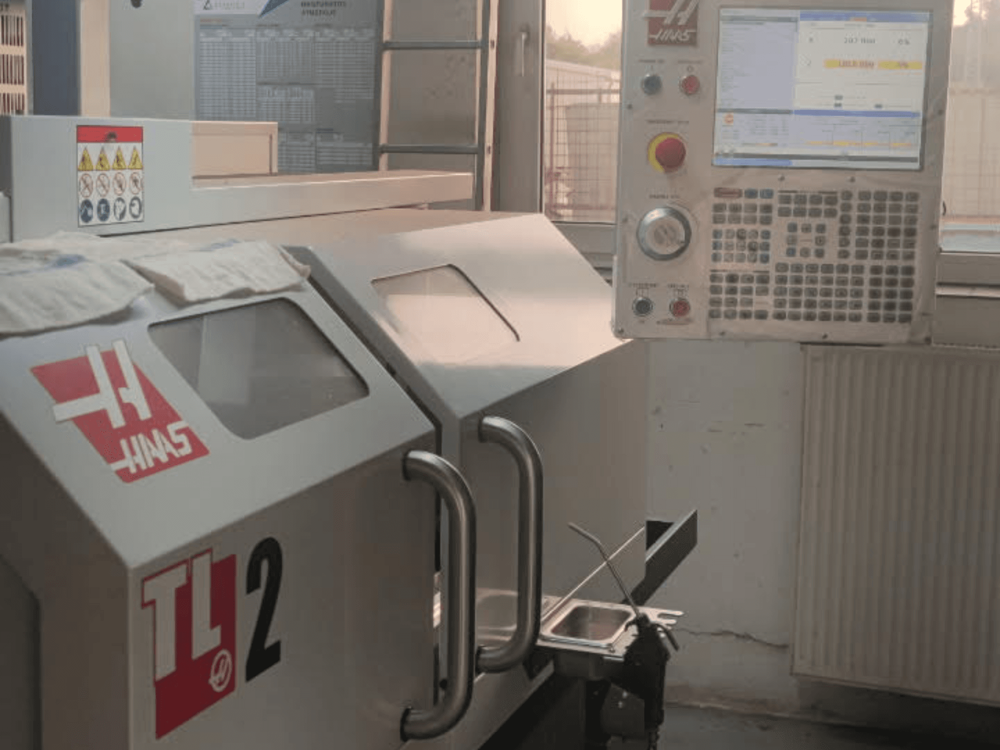 Vista frontal do torno horizontal Haas TL-2, com painel de controlo, caixa metálica e sinalização de segurança.