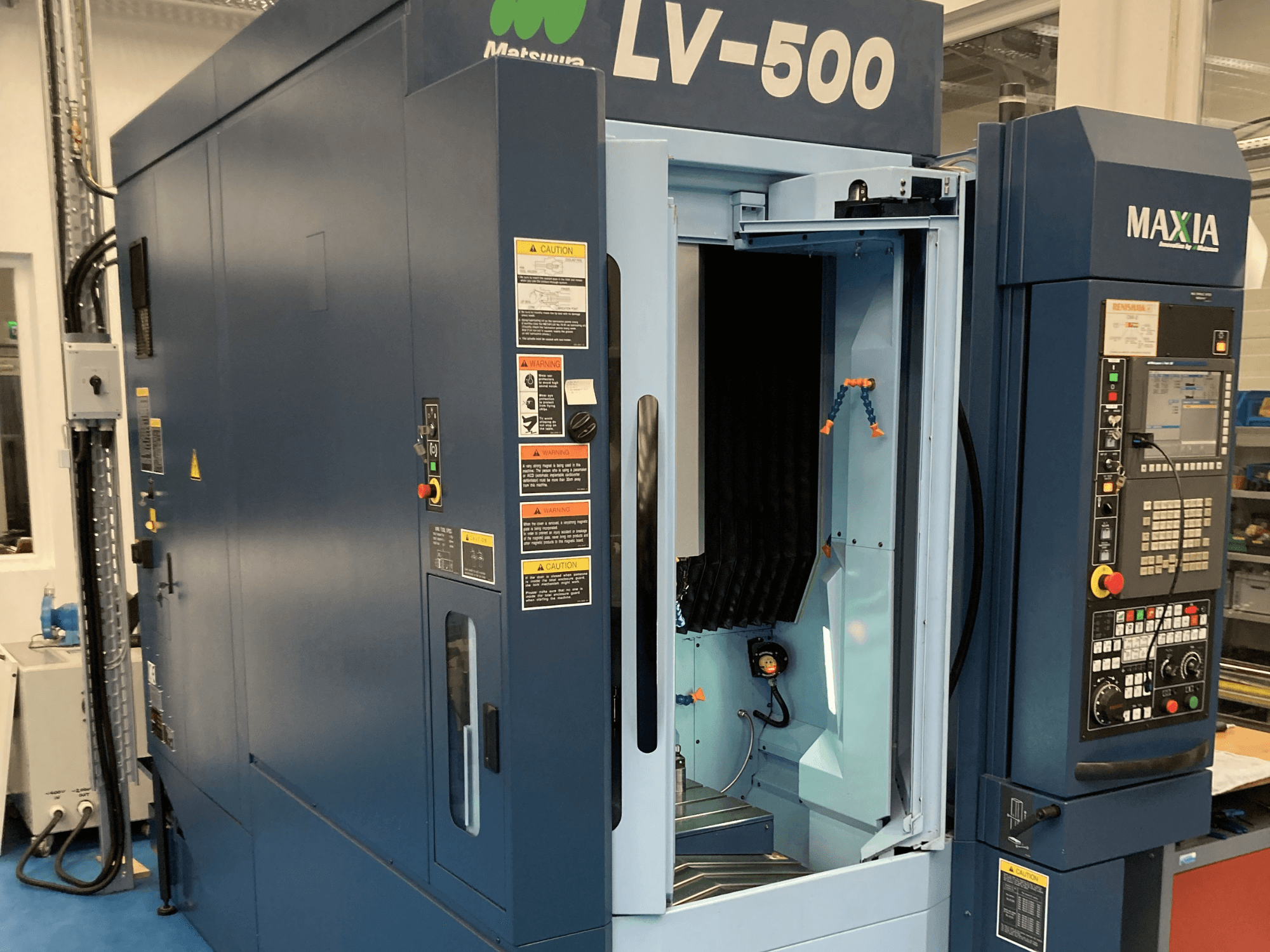 Centro de maquinação vertical Matsuura LV-500 mostrado de uma vista frontal, com uma porta aberta e um painel de controlo com botões.
