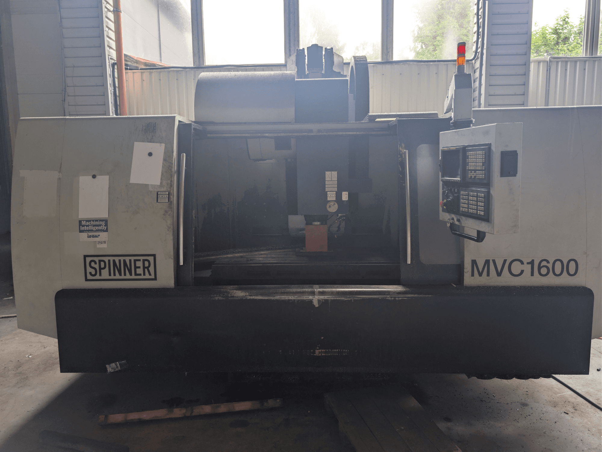 O centro de maquinagem vertical SPINNER MVC-1600, visto de frente, apresenta o painel de controlo e a área de maquinagem. Adequado para maquinagem de precisão.