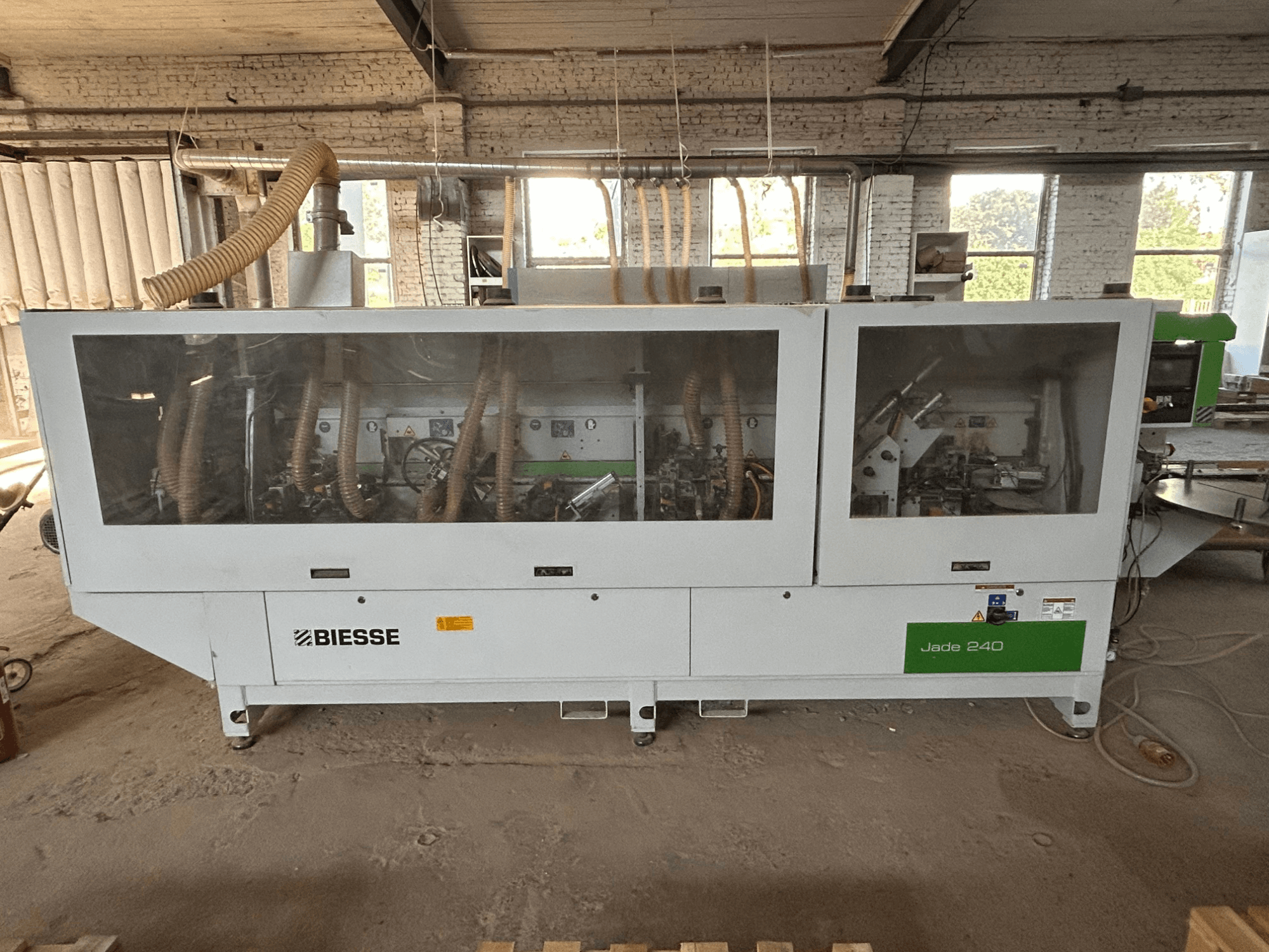 Colocadora de cantos BIESSE Jade 240 em branco e verde, vista frontal que mostra o painel de controlo e o interior detalhado da máquina.