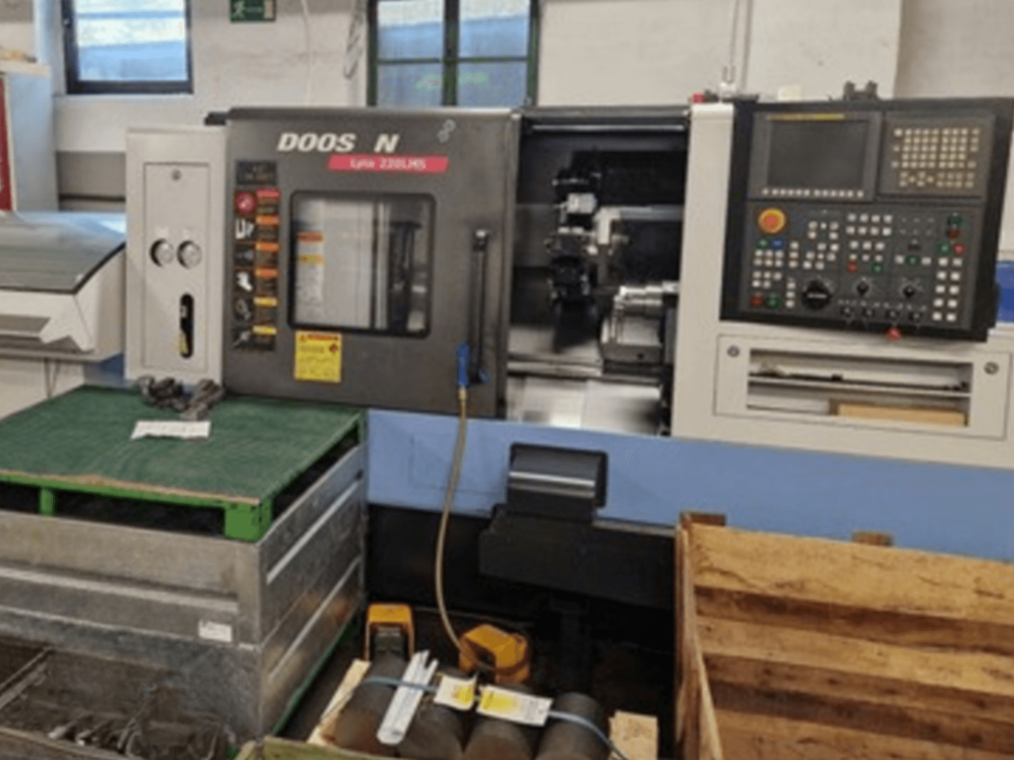 DOOSAN Lyax 220 LMS, torneiro horizontal, em vista frontal, mostrando o painel de controlo, as ferramentas e o espaço de trabalho.