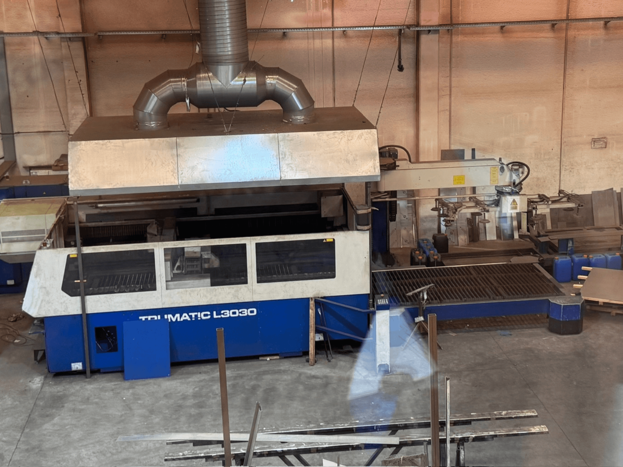 Máquina de corte a laser de CO₂ TRUMPF TRUMATIC L3030 numa oficina, vista frontal que mostra o painel de controlo e a mesa de corte.