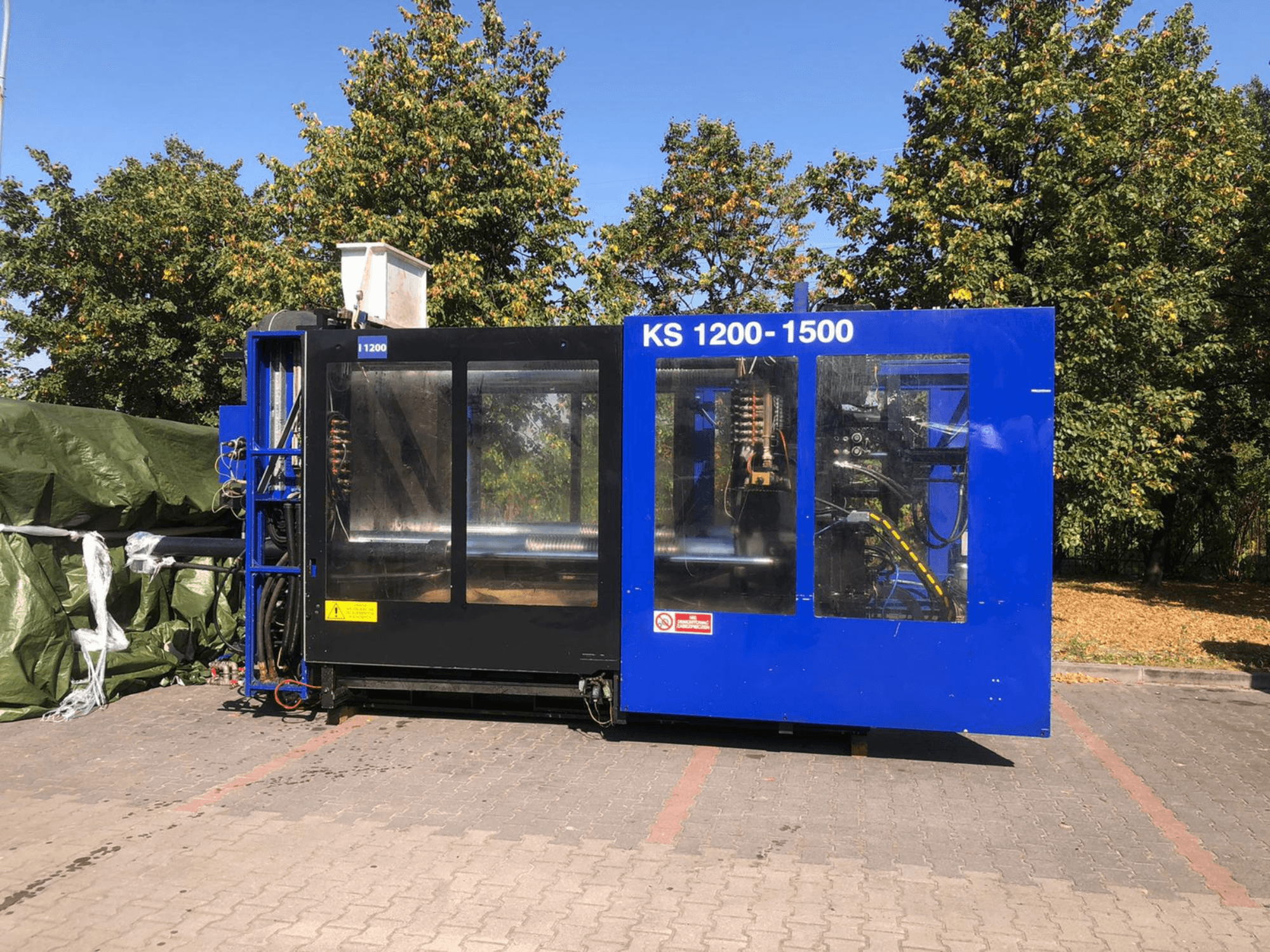 Máquina de moldagem por injeção hidráulica ITALTECH KS 1200 8300 ES, vista lateral, mostrando os comandos e os detalhes da máquina num parque.