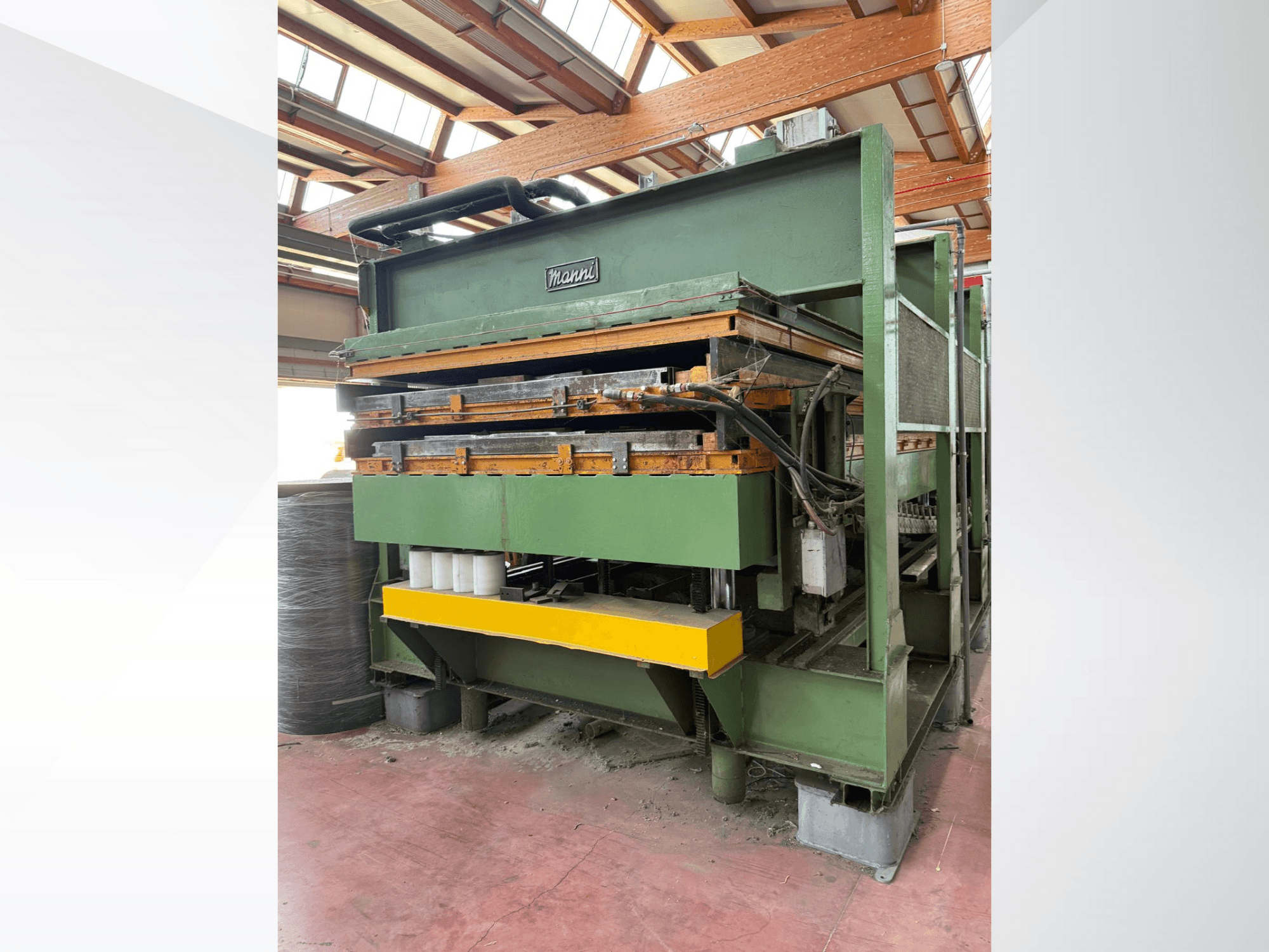 Prensa hidráulica Manni, vista lateral, com corpo metálico verde, base amarela e várias linhas hidráulicas visíveis.