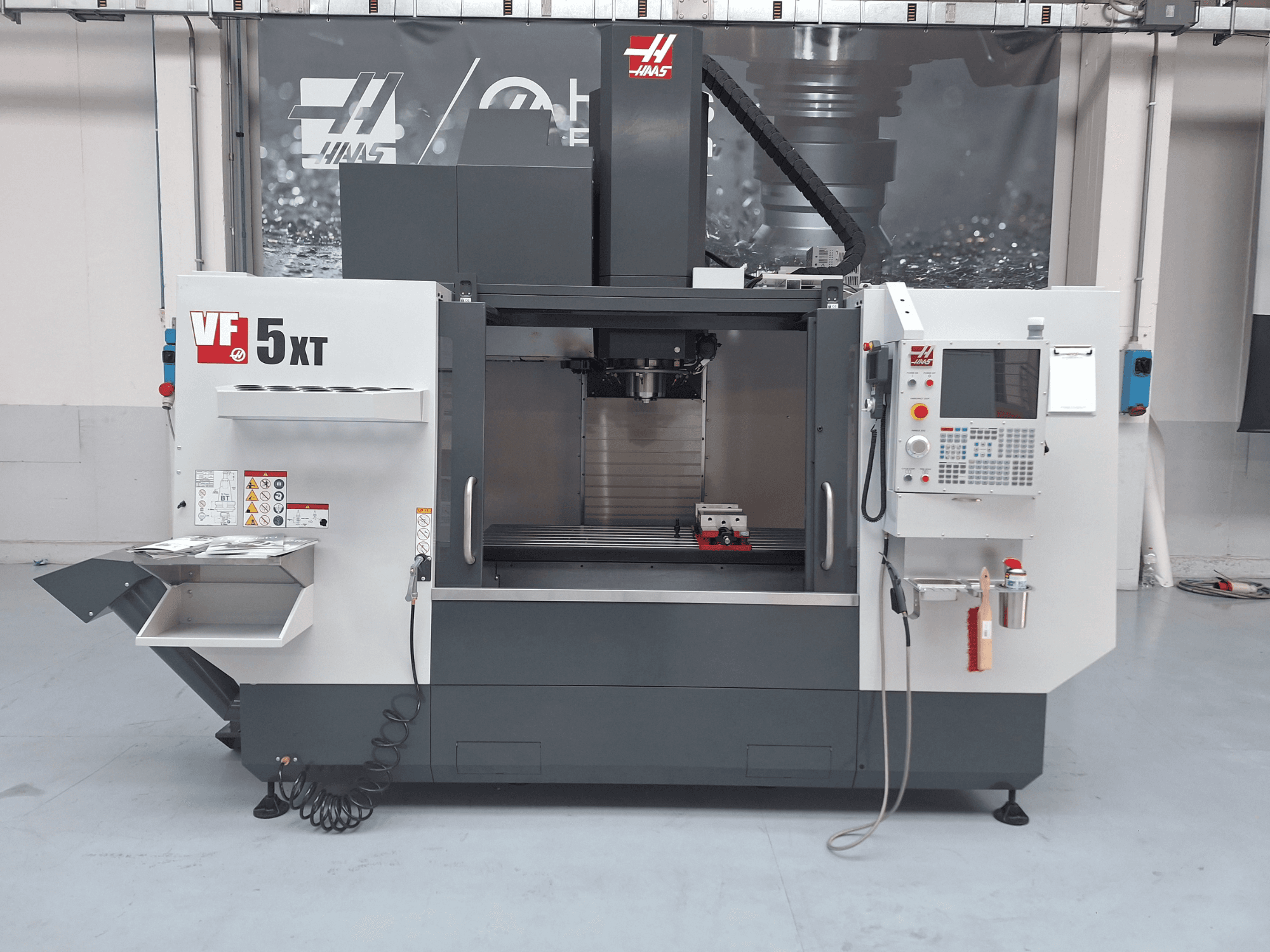 Centro de maquinagem vertical HAAS VF-5/50XT, vista frontal, mostrando o painel de controlo, a área do fuso e o compartimento de armazenamento de ferramentas.
