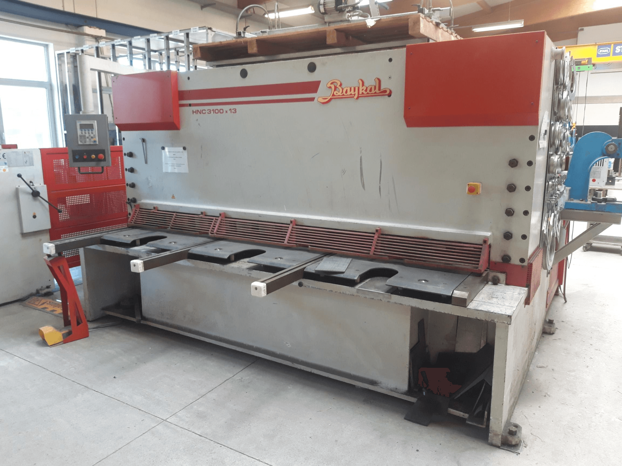 Vista frontal da máquina de corte CNC Baykal HNC 3100x13, com painel de controlo, área de corte de metal e espaço para recolha de resíduos.