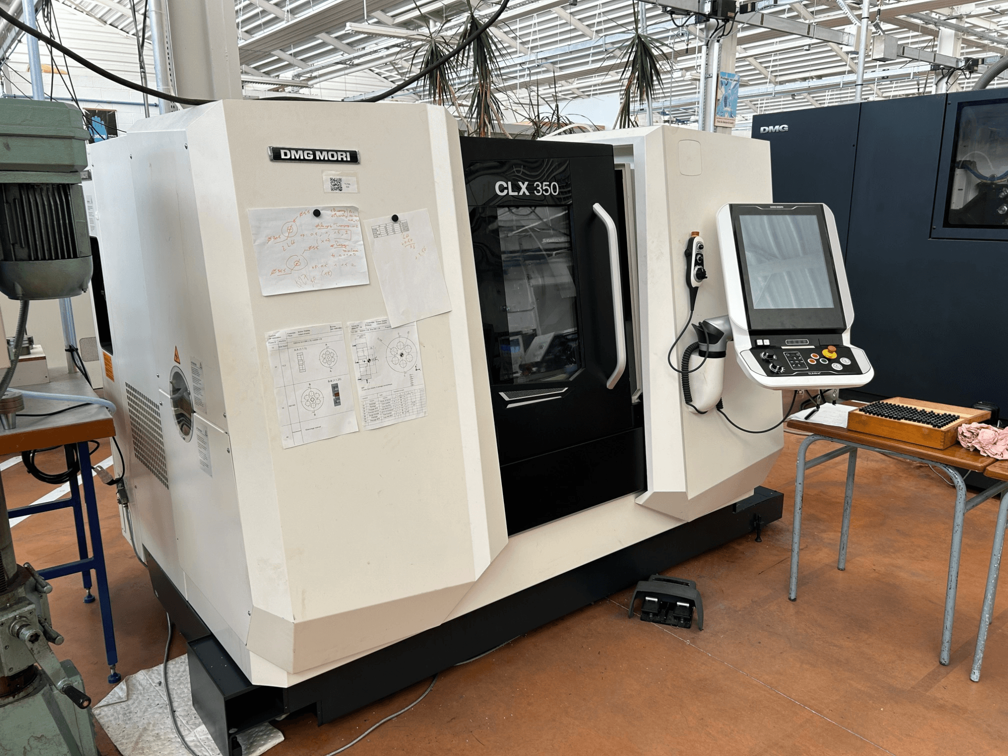 Tornos horizontais DMG MORI CLX 350 V4, vista frontal com painel de controlo e documentação técnica anexada.