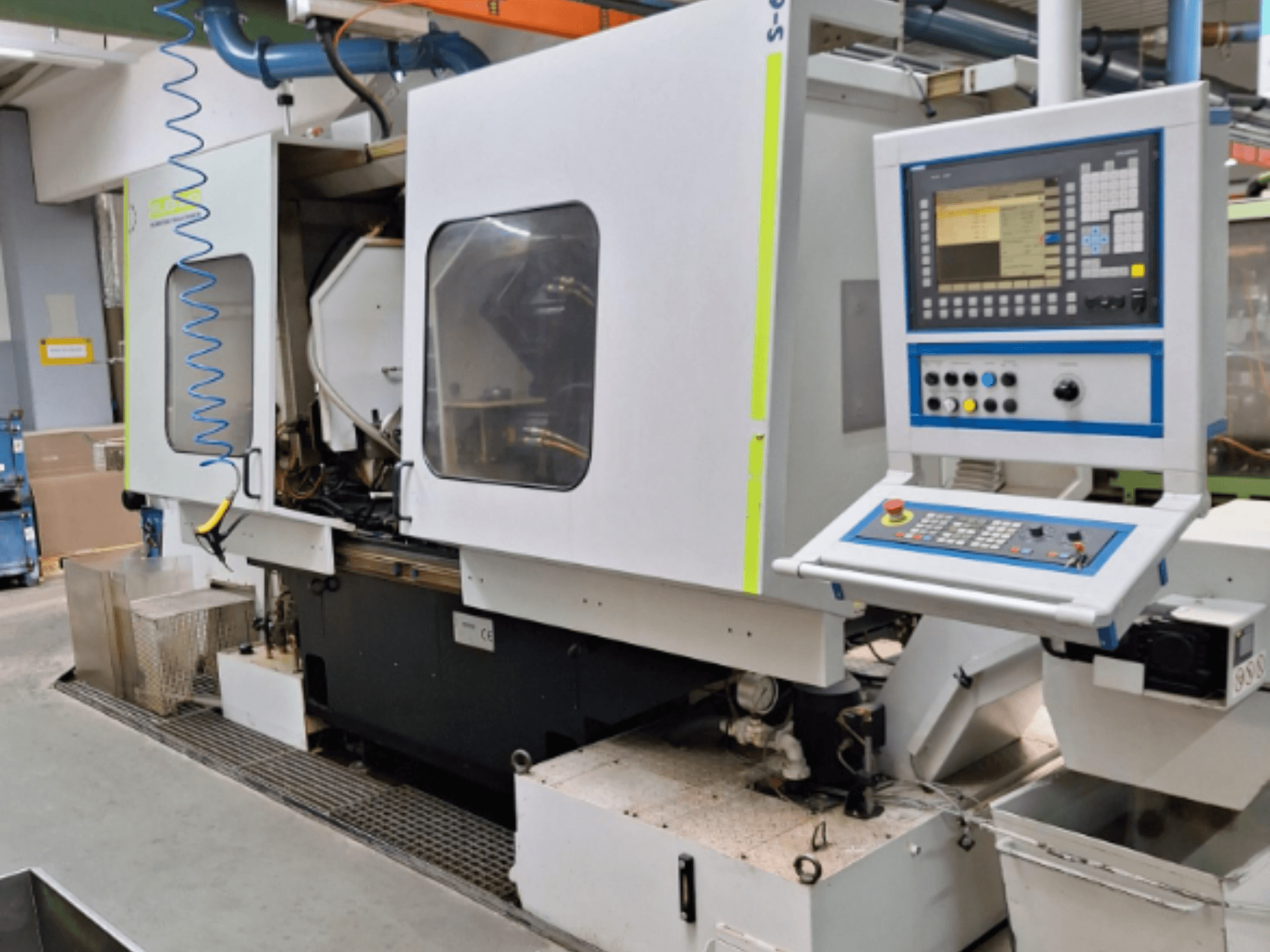 Fresadora industrial com painel de controlo, vista lateral, com câmaras duplas e ligações de tubagens visíveis.