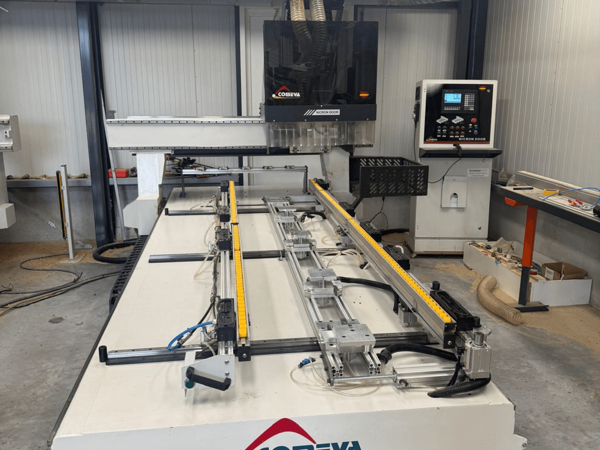 Centro de usinagem de madeira CNC COMEVA MEX V 2100x3260, vista frontal, com uma estação de trabalho, painel de controlo e calhas de guia.