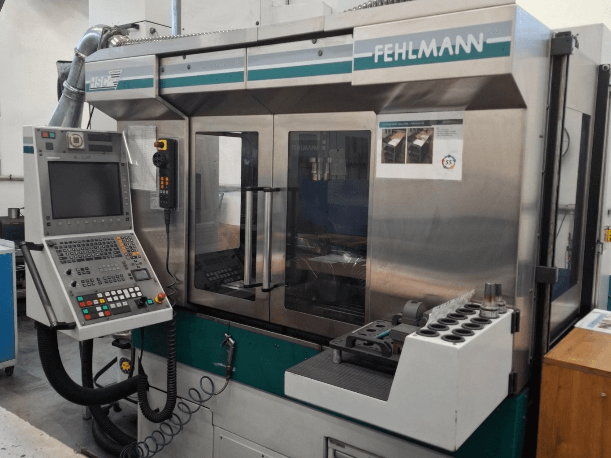 Máquina CNC Fehlmann HSC 20, vista frontal, com painel de controlo, caixa metálica e suporte de ferramentas com múltiplas ranhuras.