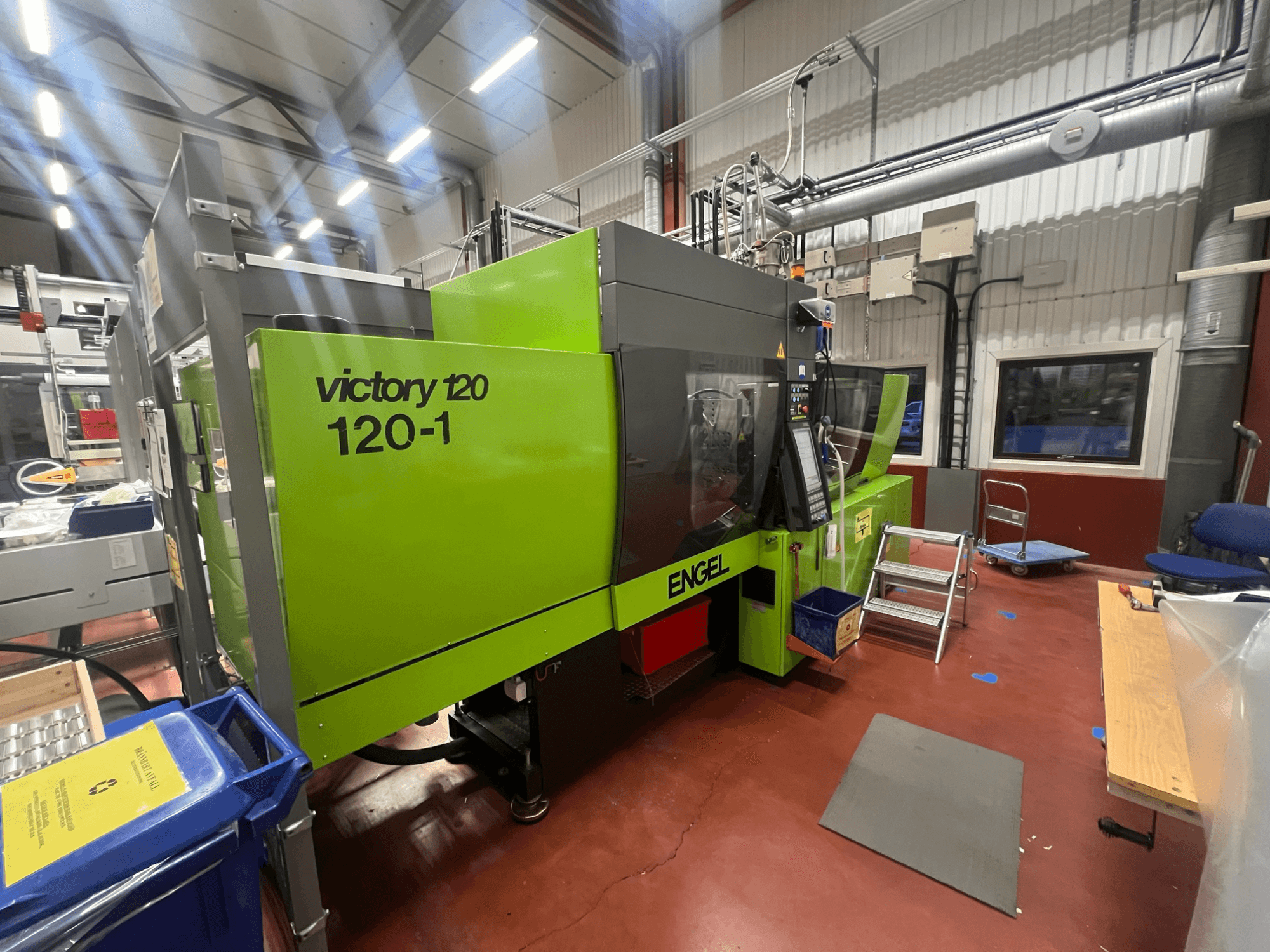 Máquina de moldagem por injeção ENGEL Victory 120-1 verde, vista frontal, com painel de controlo e degraus, em ambiente industrial.