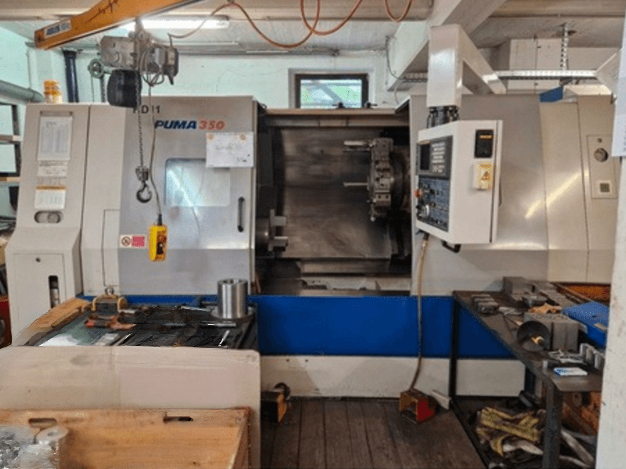 DAEWOO Puma 350 máquina de torneamento horizontal, vista lateral, mostrando o painel de controlo e a área de trabalho com ferramentas e materiais próximos.