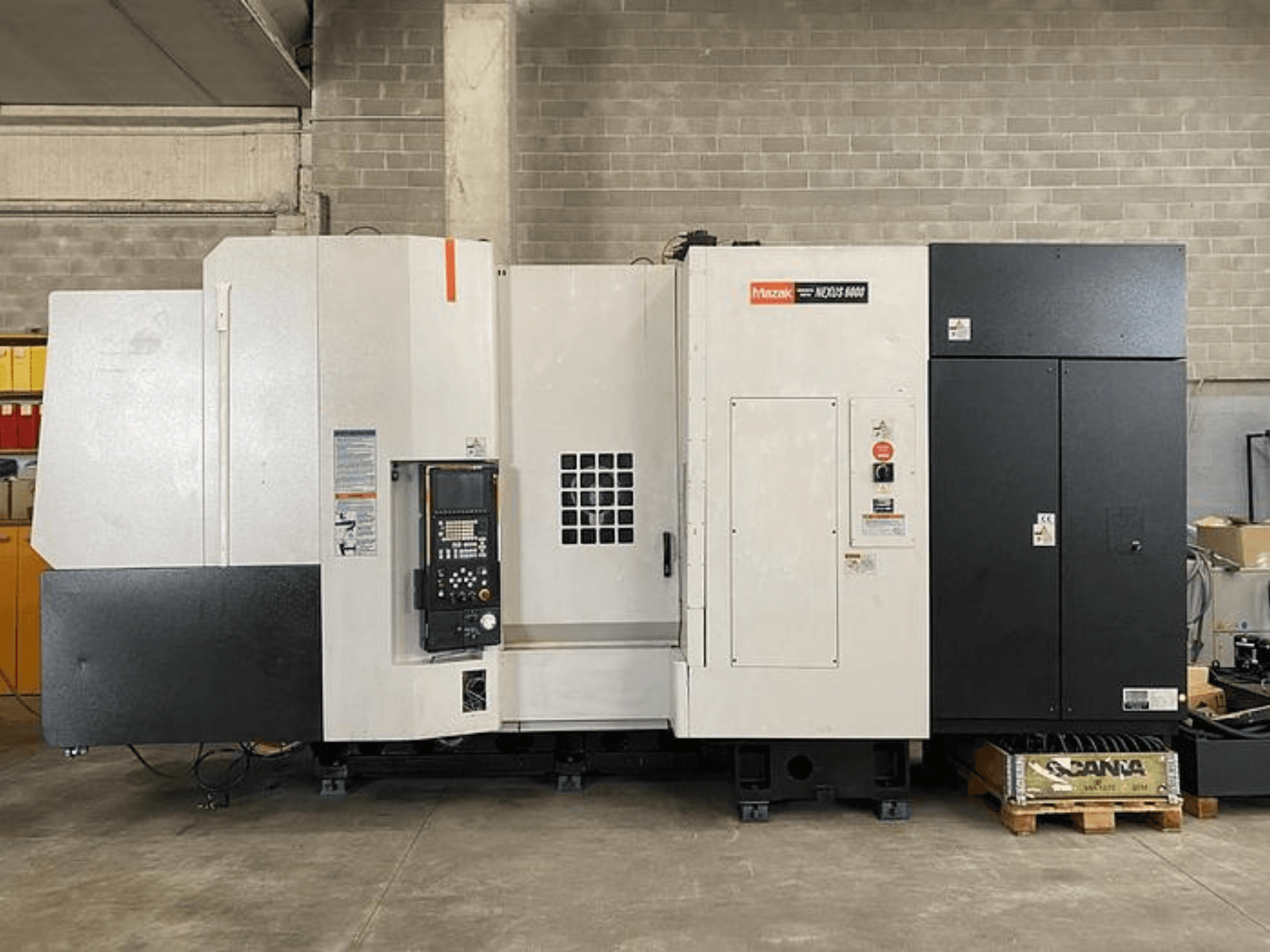 Torno CNC Mazak NEXUS 6400, vista frontal, com painel de controlo, interrutor de alimentação e caixa em dois tons de branco e preto.