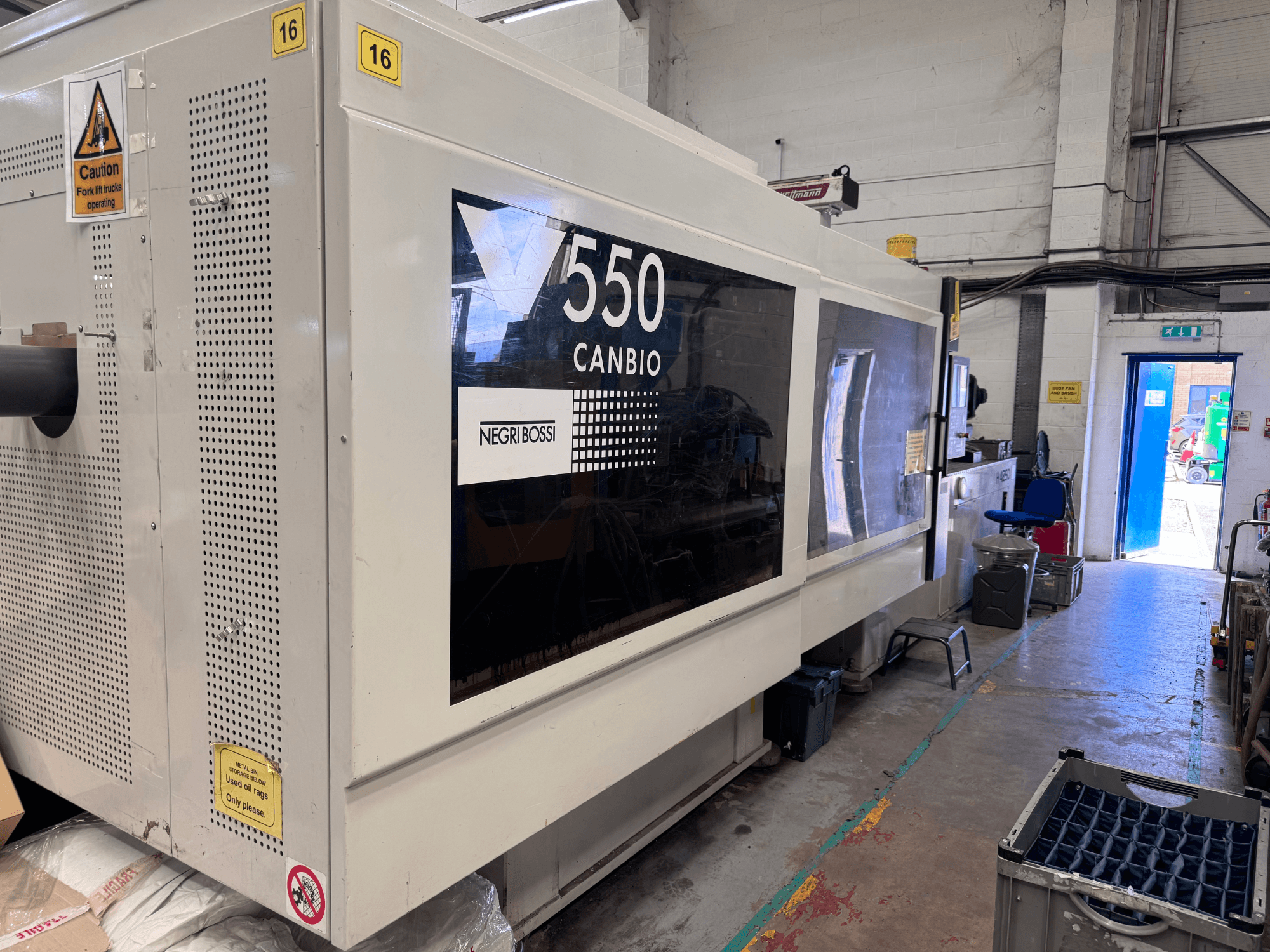 Máquina de moldagem por injeção hidráulica Negri Bossi 5500H-4250, vista frontal que mostra o painel de controlo e os sinais de aviso.