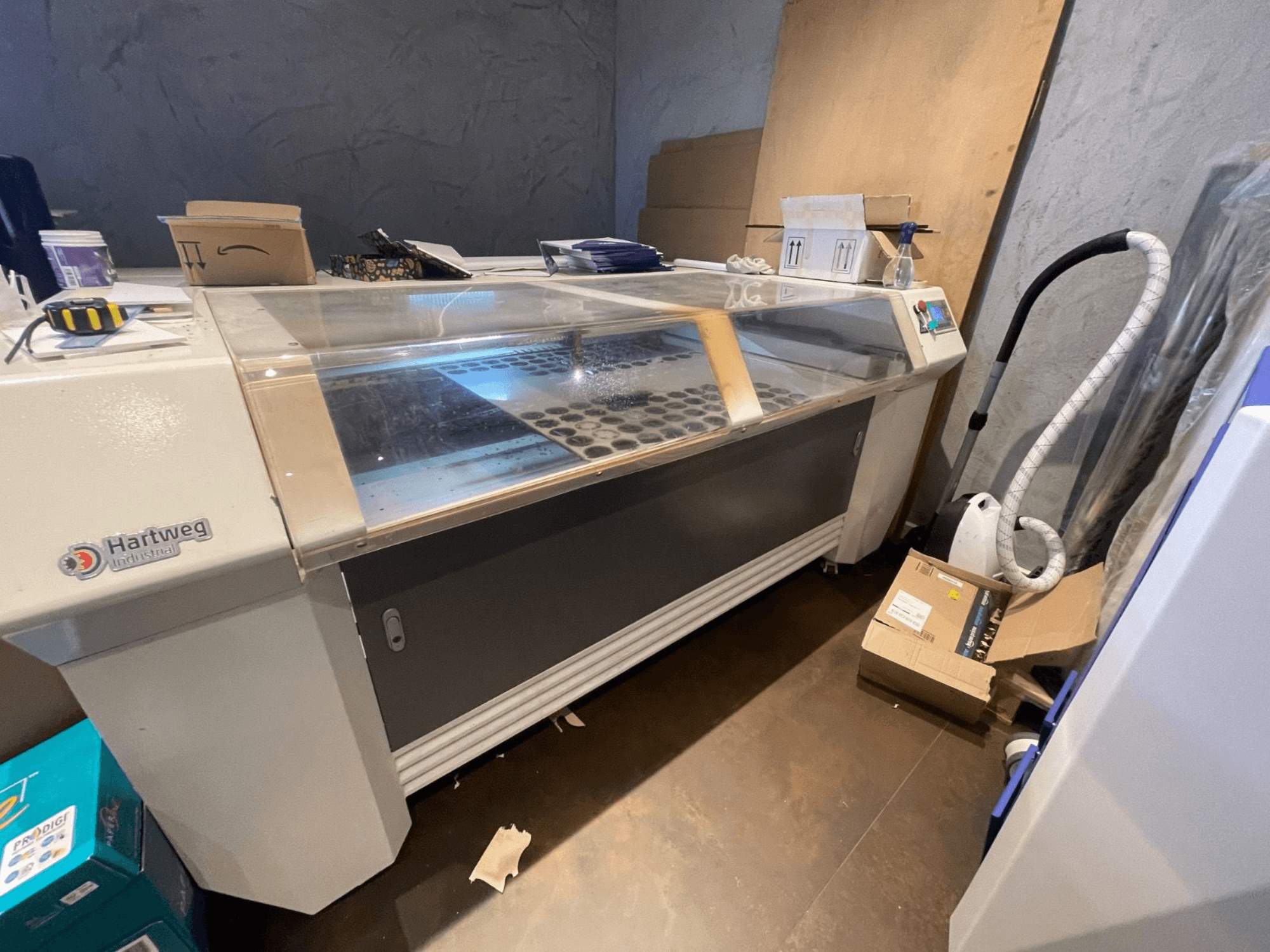 Máquina de corte a laser CO2 Bodor CL-1610XUF em vista lateral, mostrando a área de trabalho com ranhuras de material e painel de controlo.