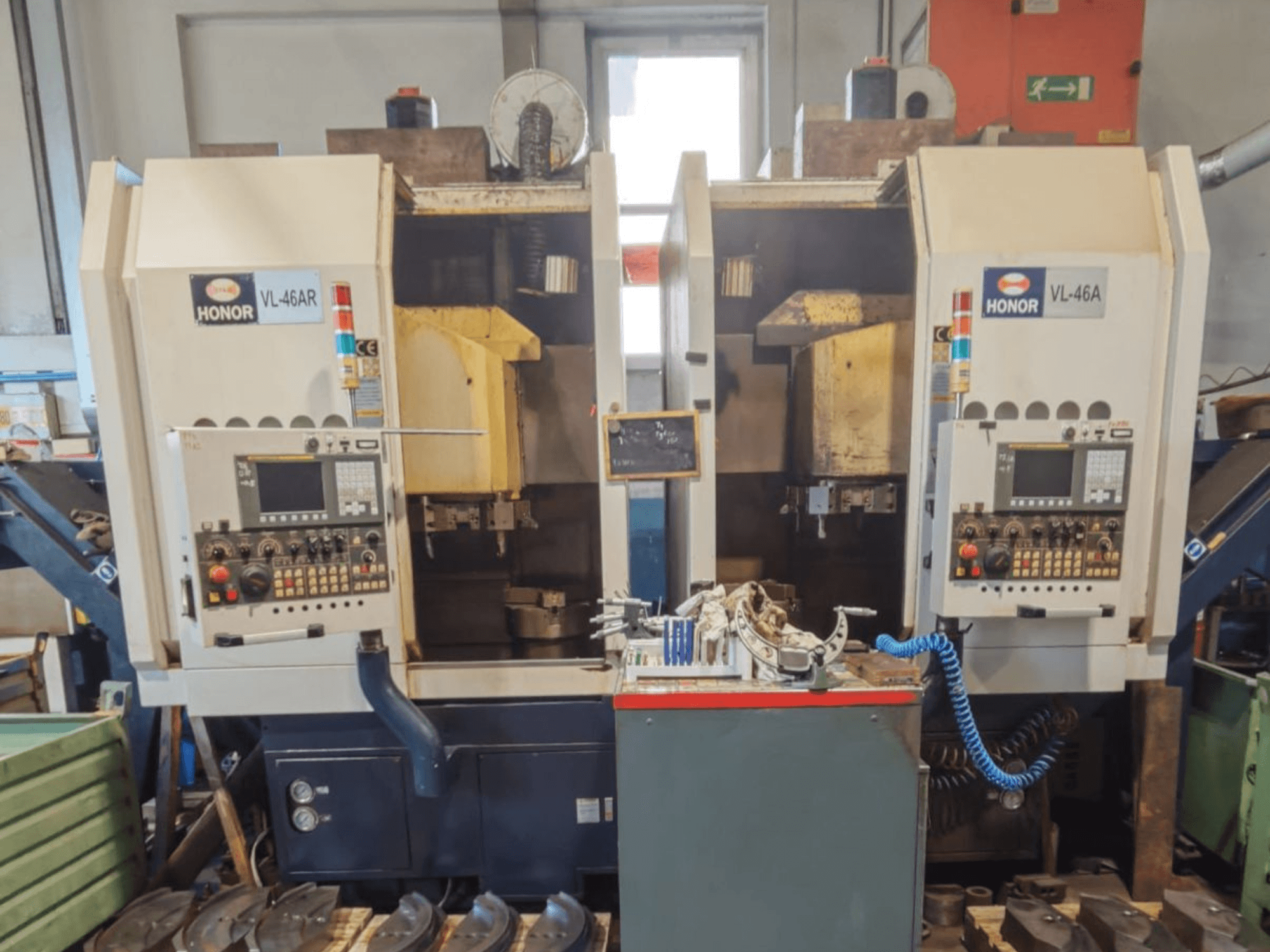 Torno vertical HONOR SEIKI VL 46 AR com duas estações de trabalho, vista frontal que mostra os painéis de controlo e as ferramentas.