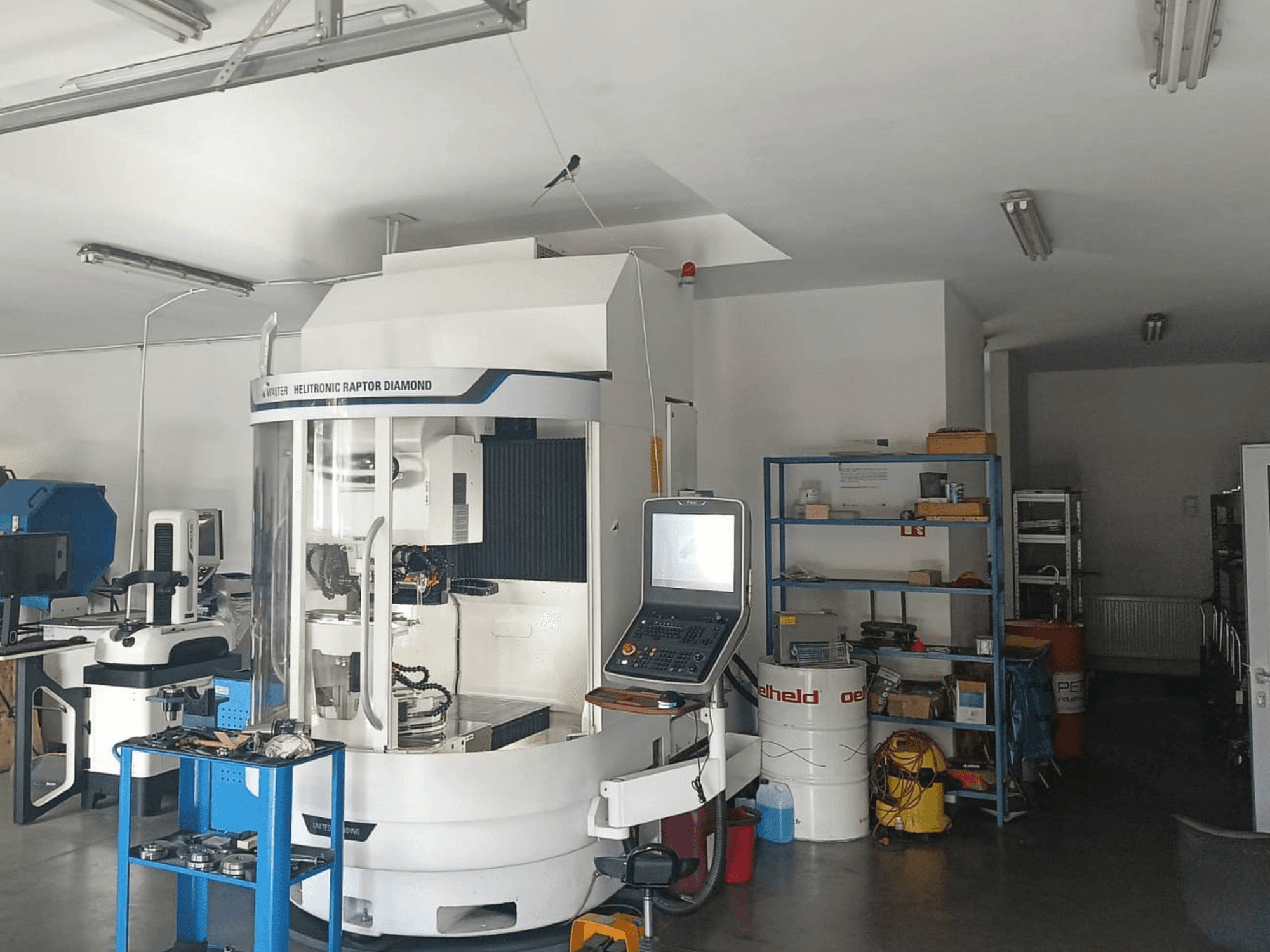 Máquina de retificação cilíndrica WALTER HELITRONIC RAPTOR DIAMOND numa oficina, vista lateral com o painel de controlo e as ferramentas nas proximidades.