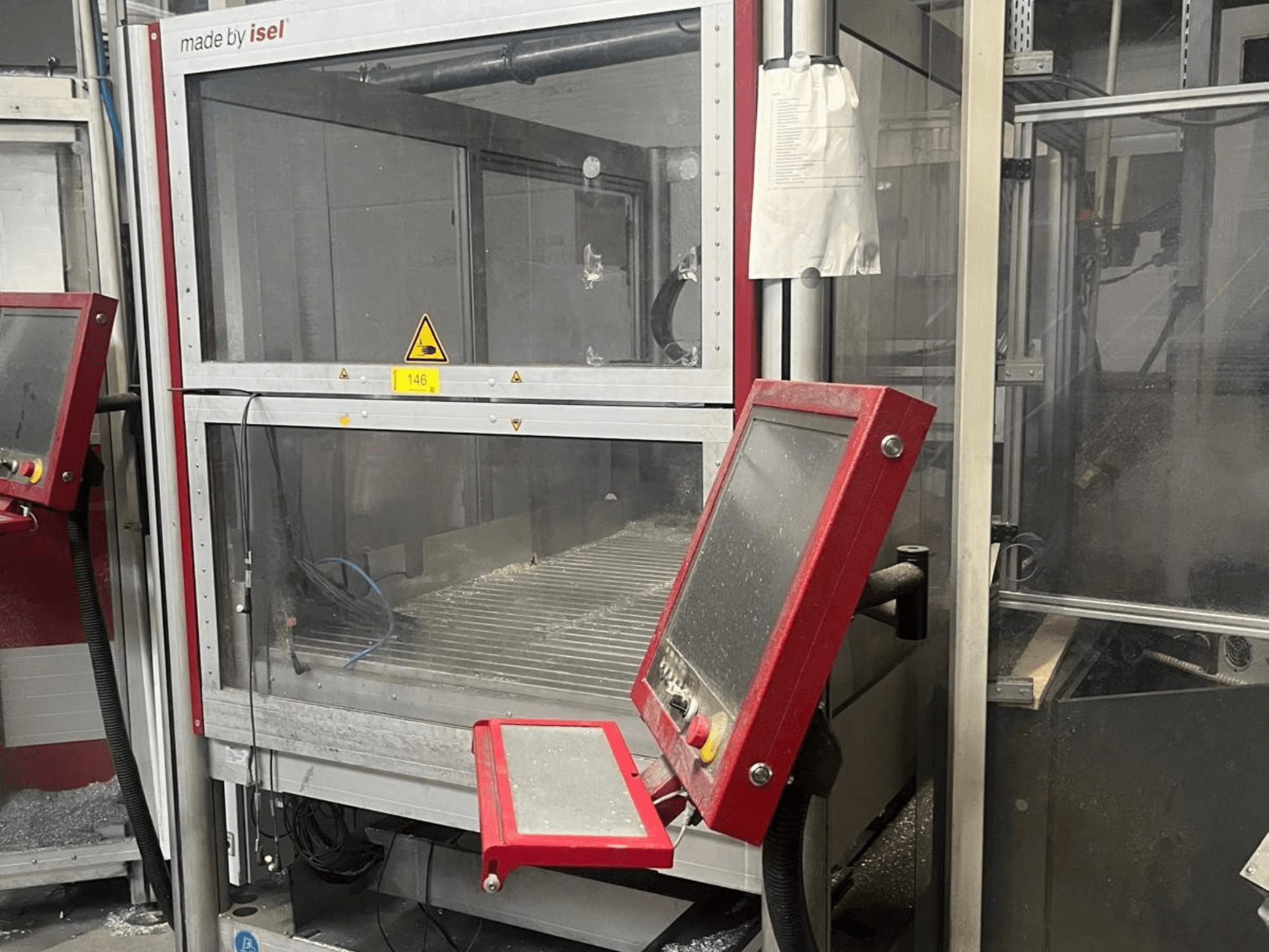 Centro de maquinagem vertical ISEL FLATCOM M 30, vista frontal que mostra o painel de controlo, a área de trabalho e os dispositivos de segurança.
