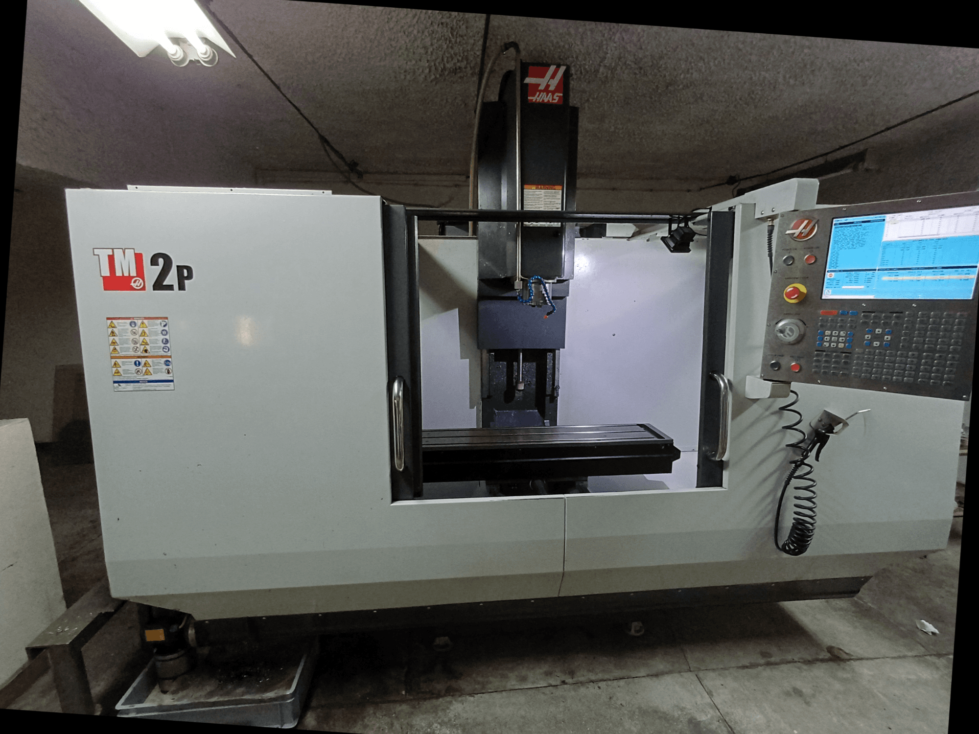 Centro de maquinação vertical HAAS TM-2P, vista frontal, mostrando o painel de controlo, a cabeça do fuso e a base da máquina.