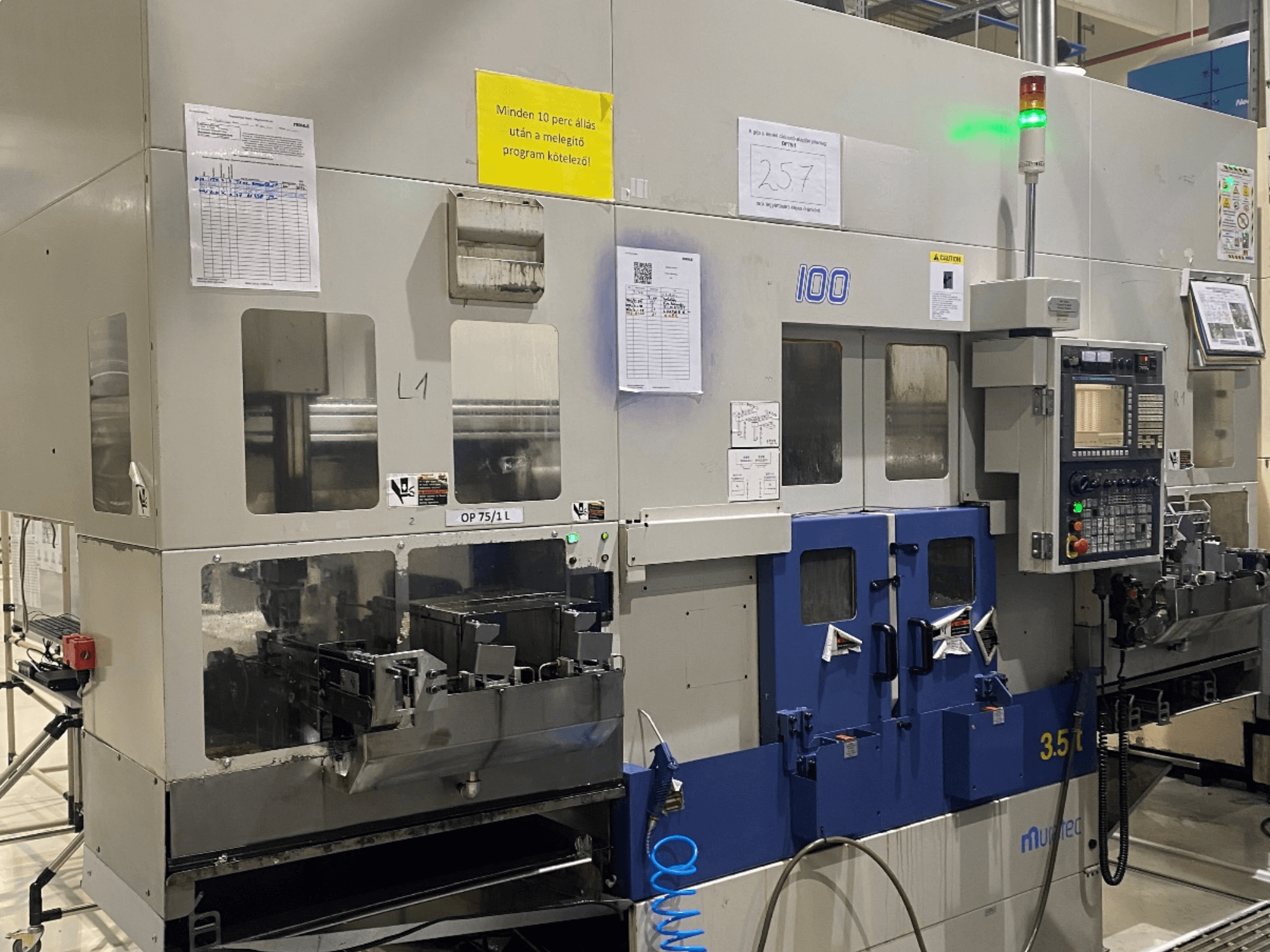 Torno horizontal MURATA MW100 num ambiente de fábrica, vista frontal que mostra o painel de controlo e detalhes operacionais.
