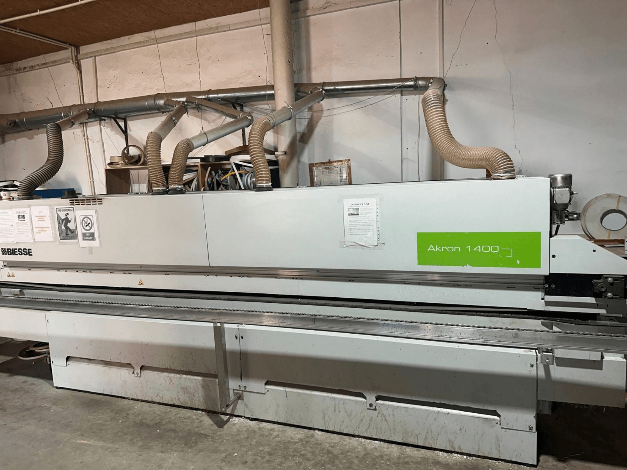 Máquina de colagem de bordas BIESSE Akron 1440 A vista de lado, com condutas, painel de controlo e autocolantes operacionais.