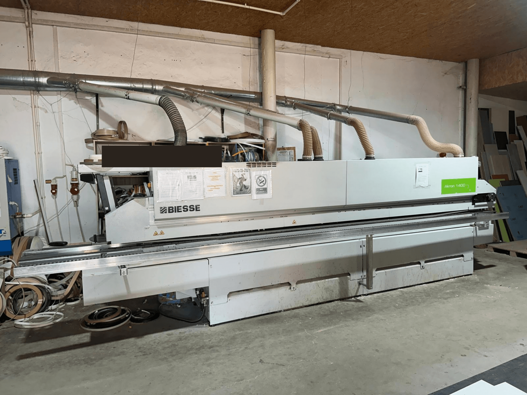 Colocadora de bordas BIESSE AKRON 1440 A, vista frontal, com o painel de comando visível e os componentes de extração de pó num ambiente de oficina.