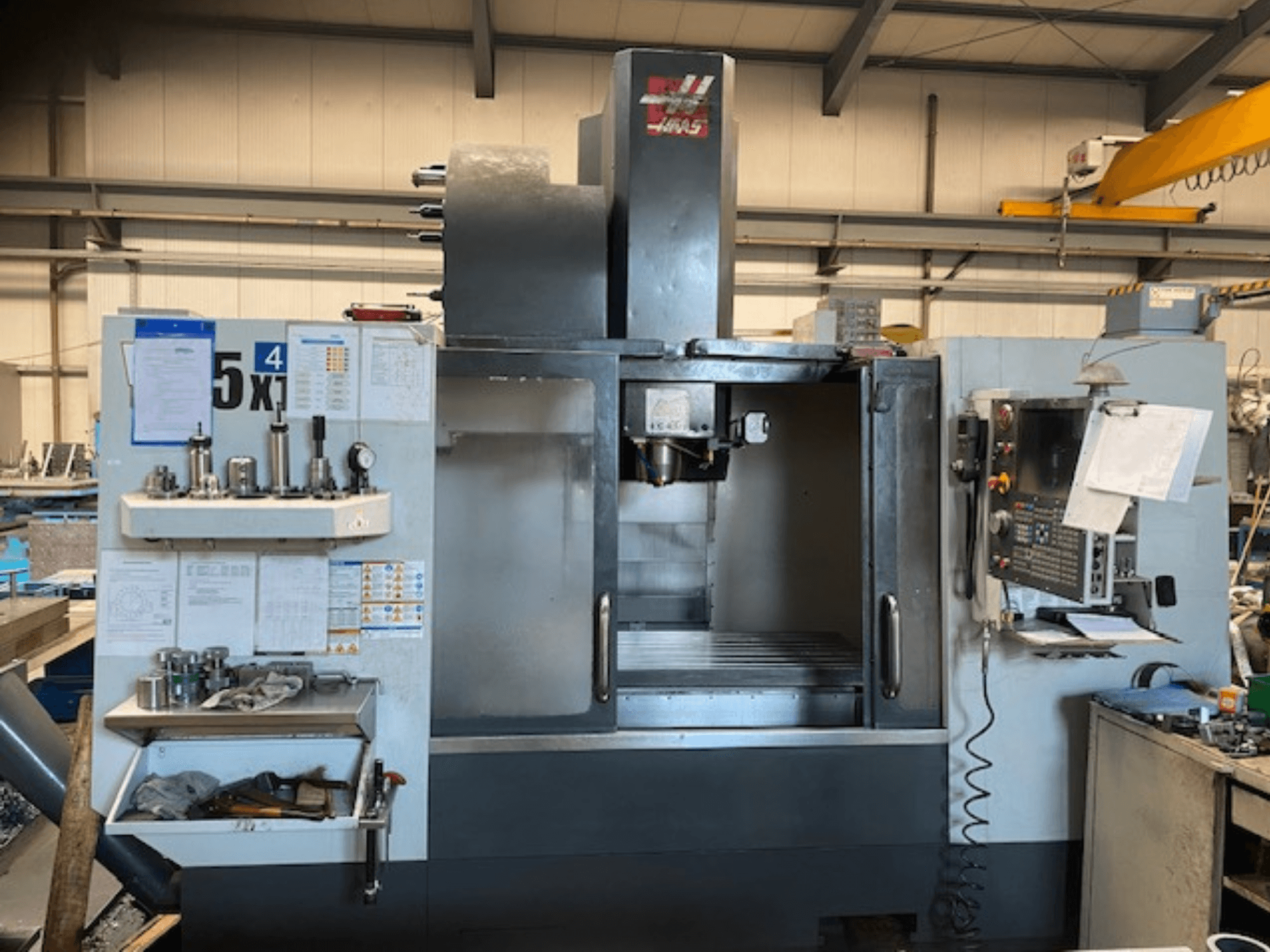 Centro de maquinação vertical Haas VF-5, vista frontal, mostrando o painel de controlo, armazenamento de ferramentas e área do spindle.