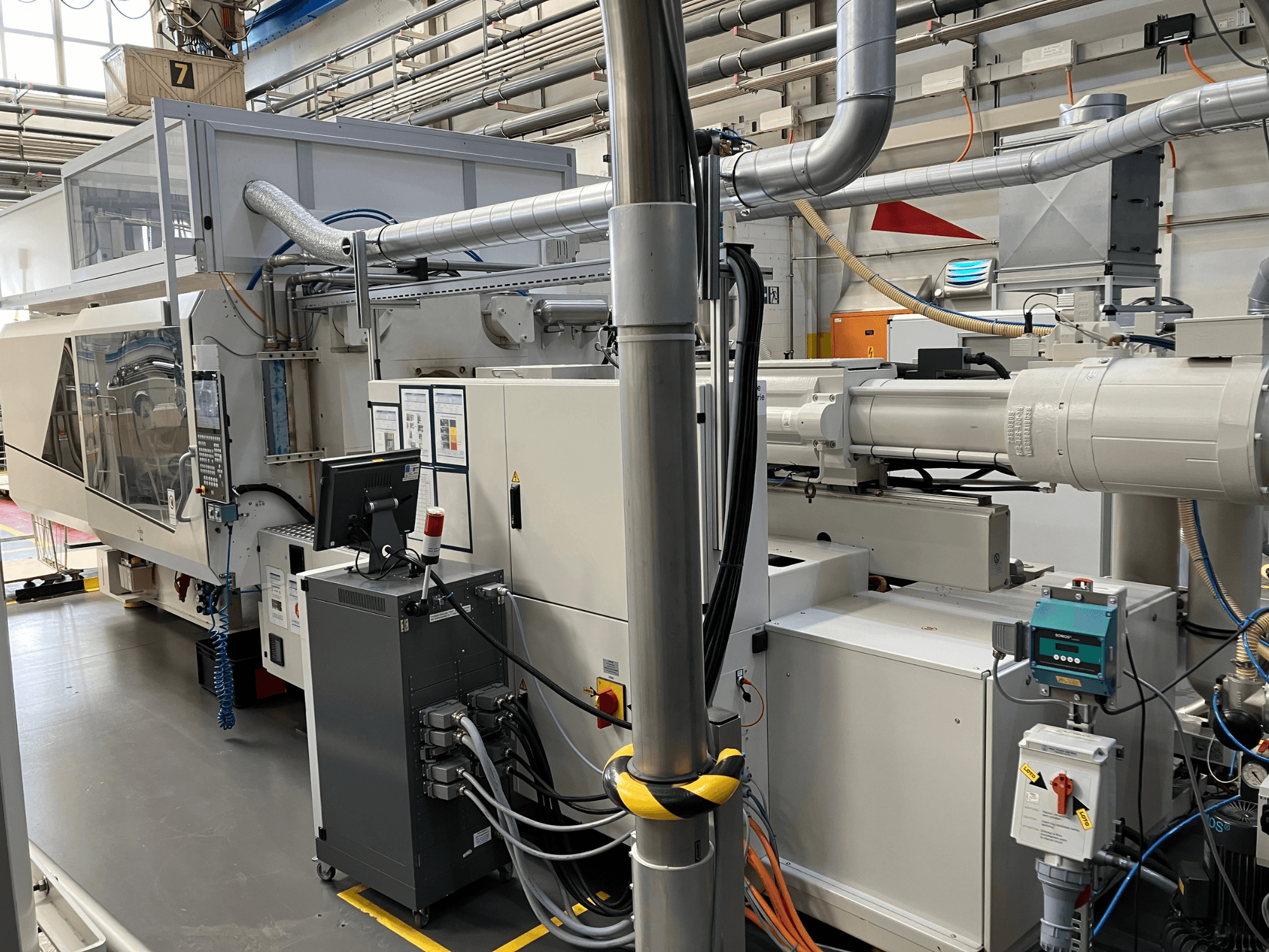 Máquina industrial com painel de controlo, vista frontal, com tubagens, componentes eléctricos e elementos de segurança.