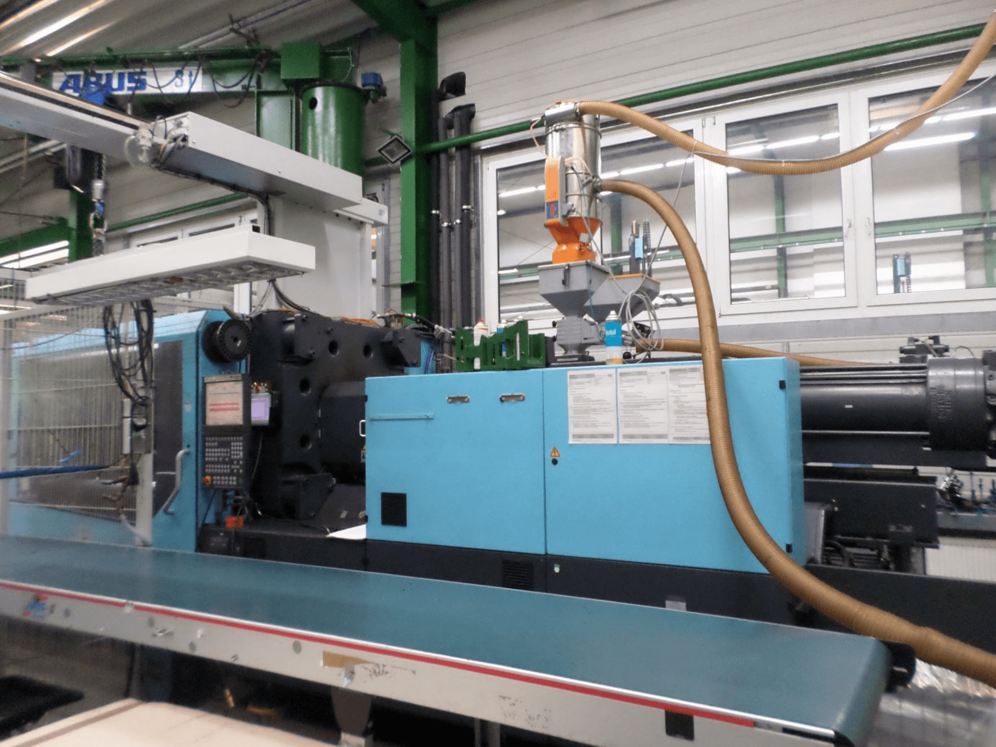 Vista frontal de uma máquina de moldagem por injeção hidráulica DEMAG D 420, mostrando o painel de controlo, o funil e os componentes hidráulicos.