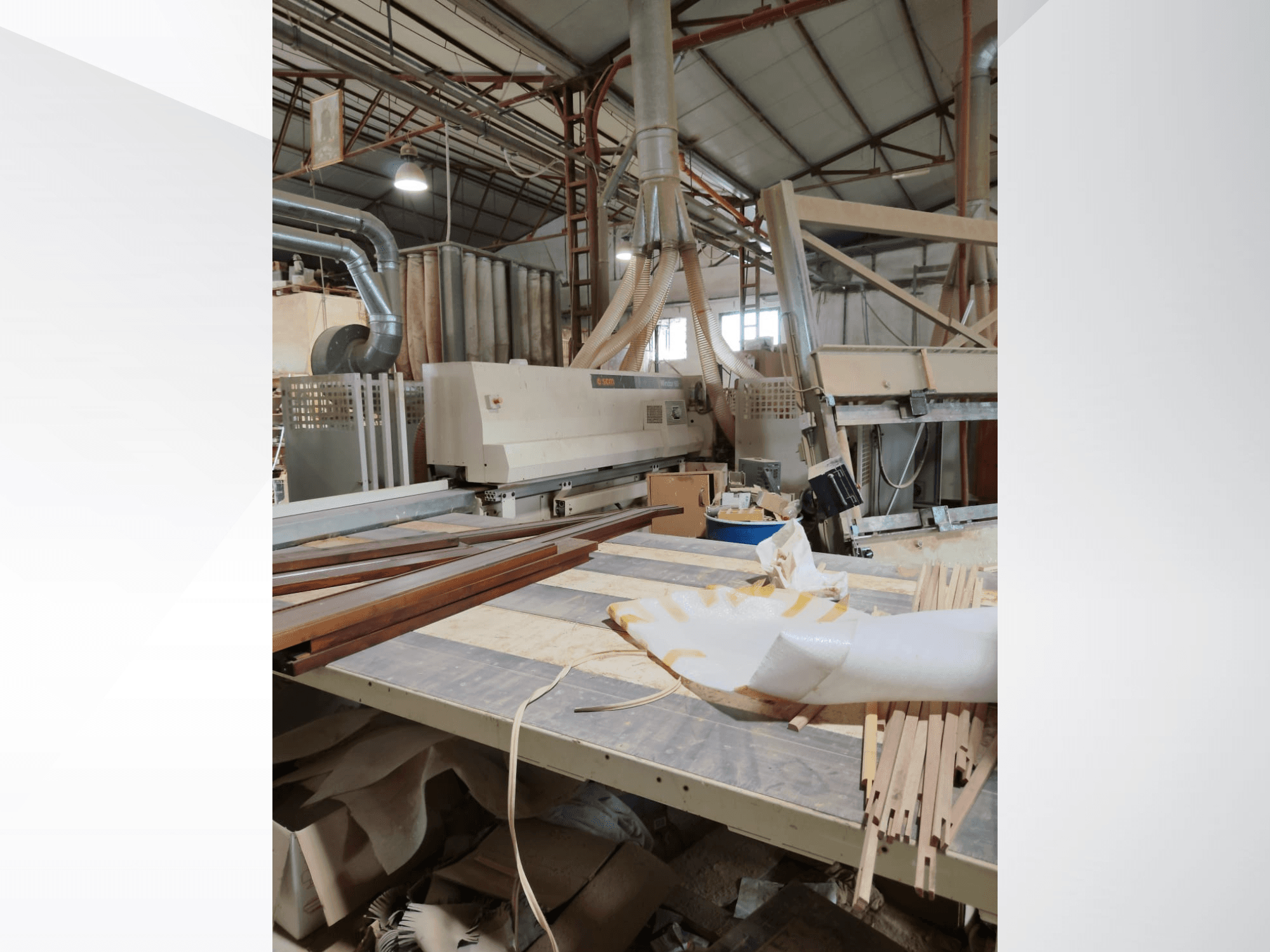 Centro de maquinação CNC para madeira SCM Windor60 numa oficina, visto de lado com painéis de madeira e equipamento de extração de poeiras.