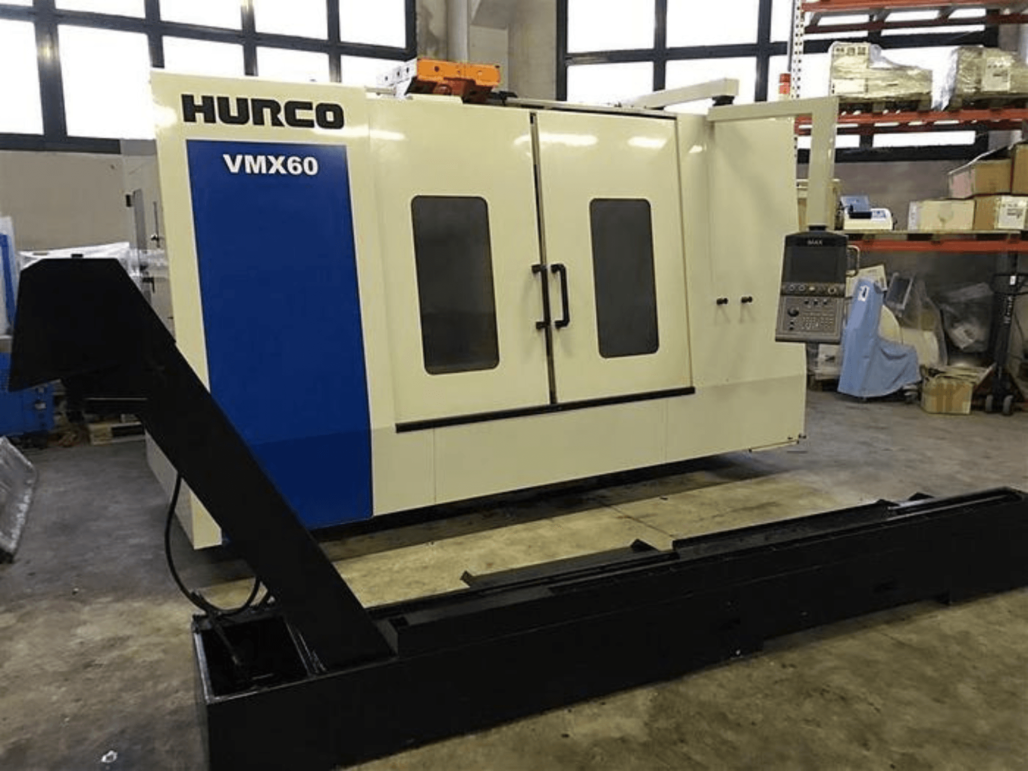 Máquina CNC VMX60 da HURCO numa oficina, vista frontal, com um painel de controlo e uma calha de suporte preta anexada.