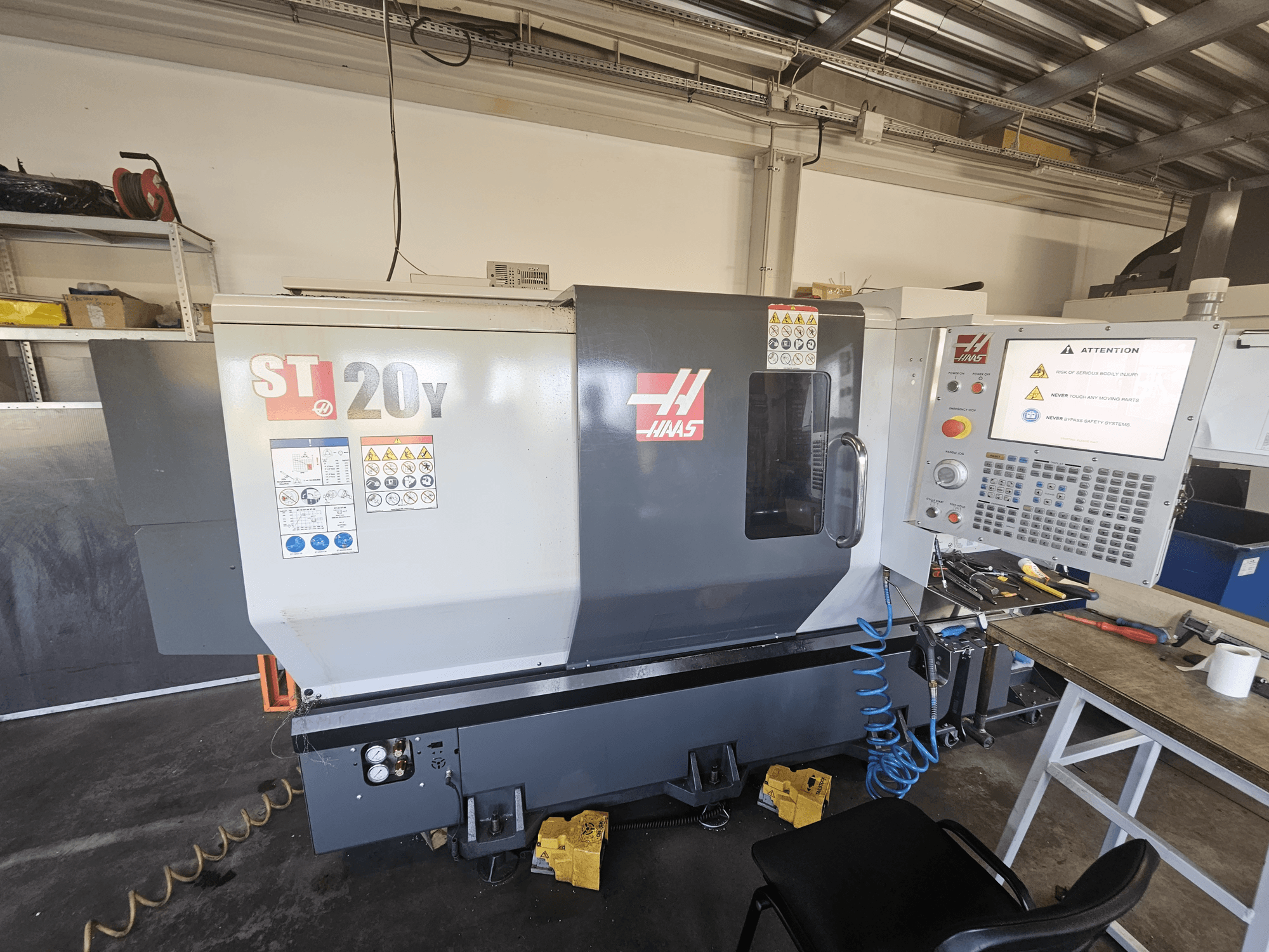 Torno CNC ST-20Y da Haas, vista frontal; inclui painel de controlo, avisos de segurança e mangueira de ar.