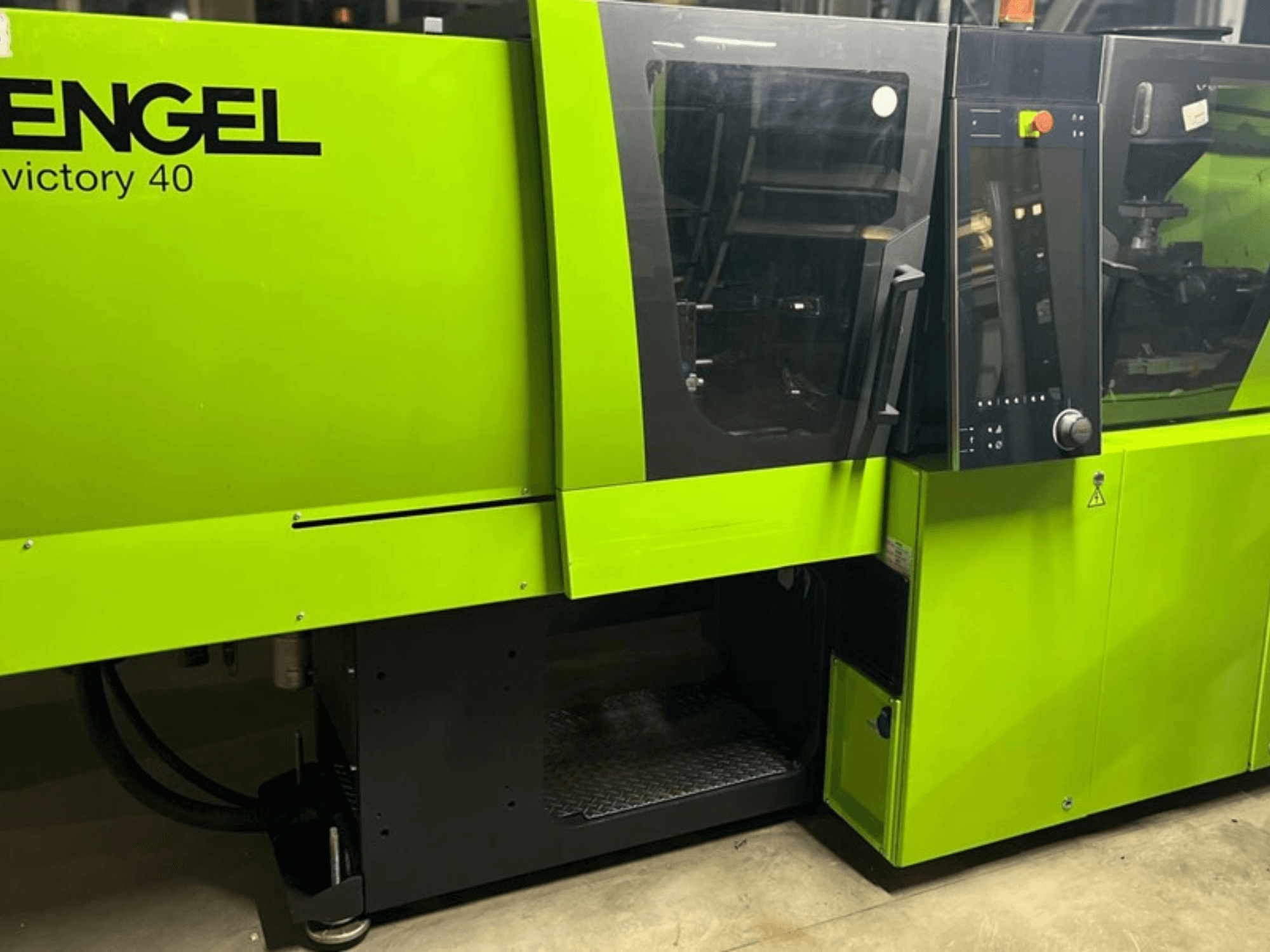 Máquina de moldagem por injeção ENGEL Victory 40 em verde brilhante, vista frontal mostrando o painel de controlo e a porta de acesso com etiqueta de aviso.