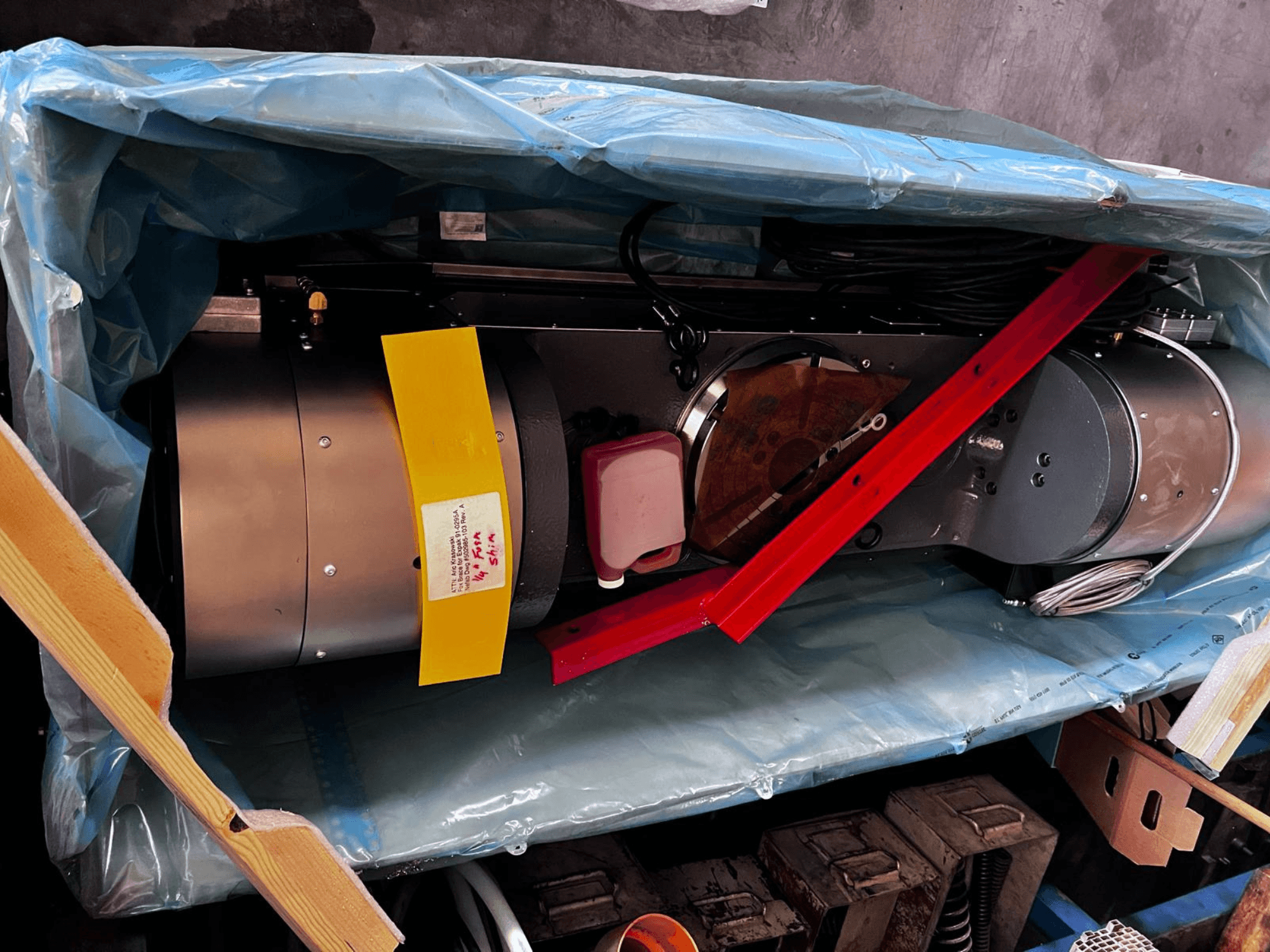 Dispositivo motor parcialmente visível na embalagem, apresenta um exterior prateado, indicadores coloridos e suporte vermelho.