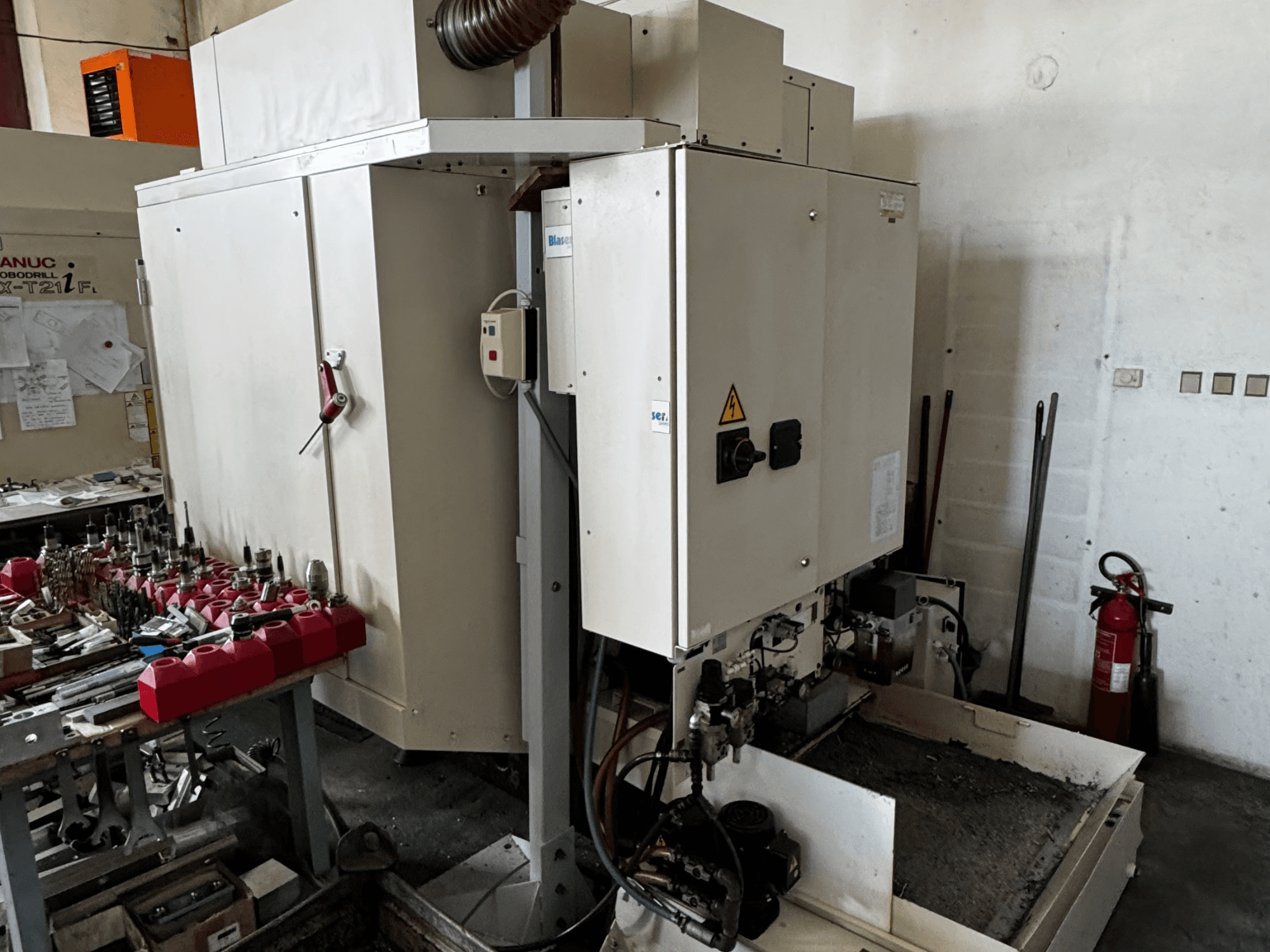 Centro de maquinação vertical FANUC Robodrill alpha-T21iFL, vista lateral mostrando o painel de controlo, ferramentas e espaço de trabalho.