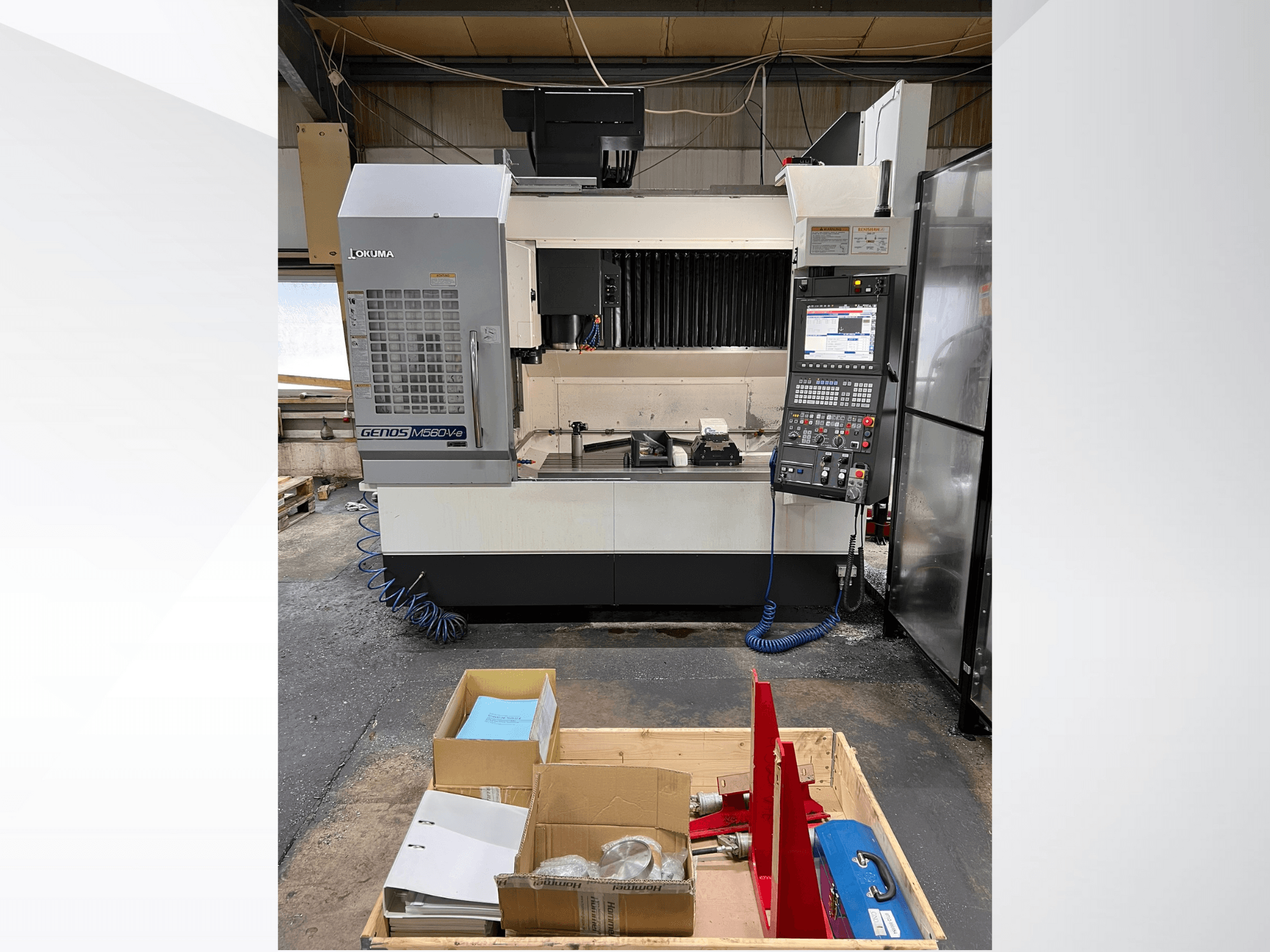 Centro de maquinação vertical Okuma GENOS M460V-5, vista frontal, com painel de controlo visível e ferramentas na mesa de trabalho.